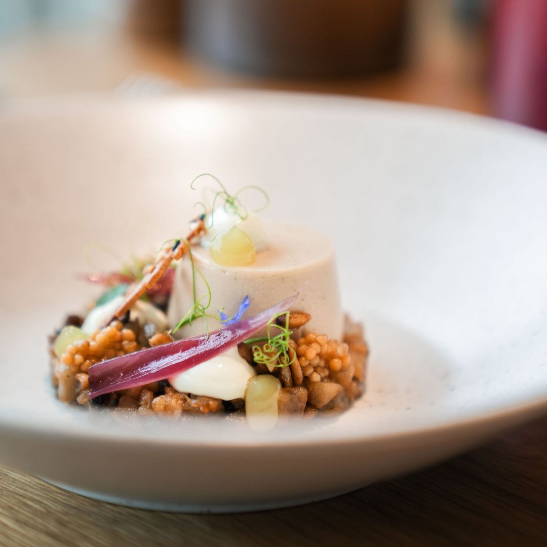Fein angerichtete Gourmet-Vorspeise mit Creme, Perlen, Zwiebel und Kräutern