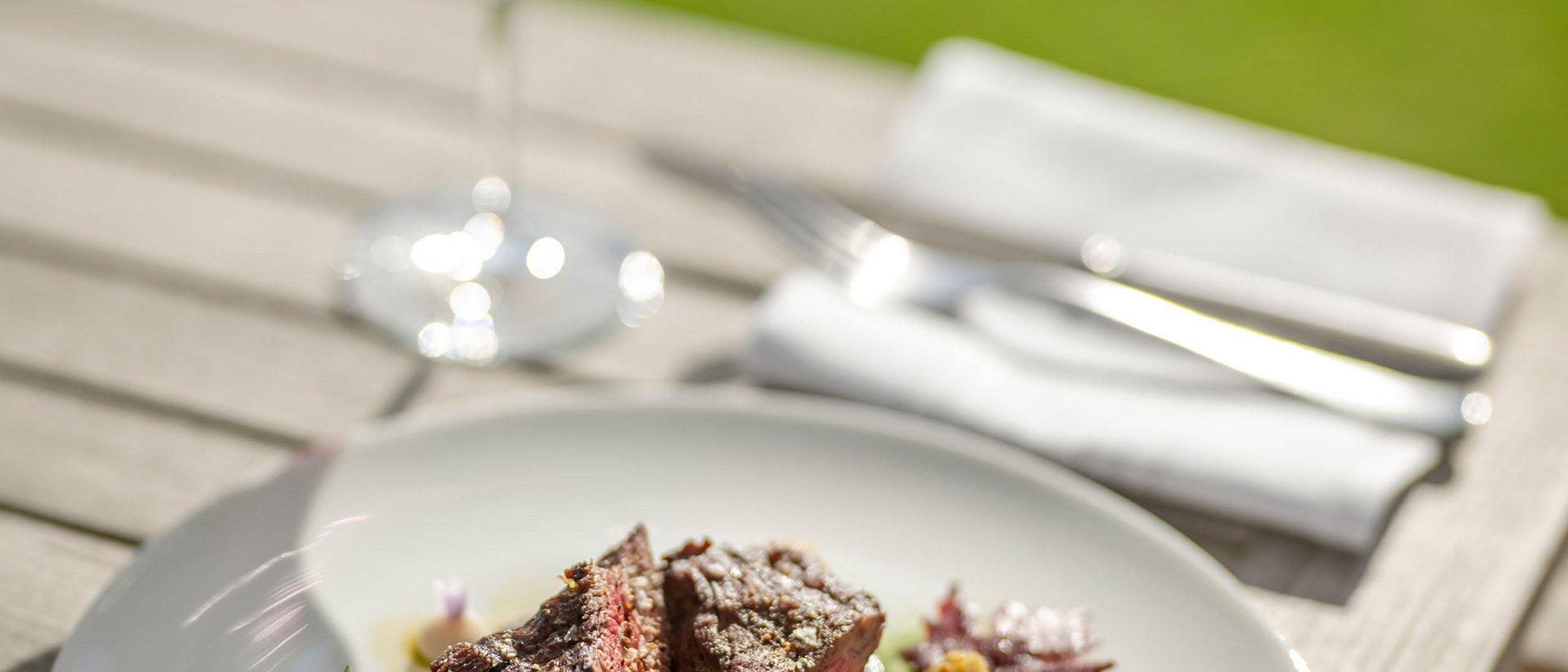 Steak avec légumes sur assiette blanche et verre de vin rouge en plein air