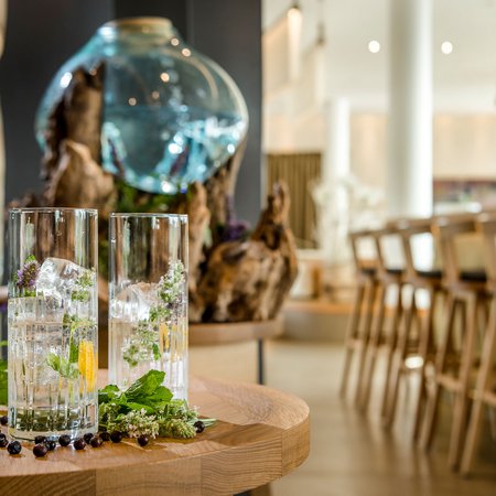 Two glasses with ice and herbs on a wooden table in a bar