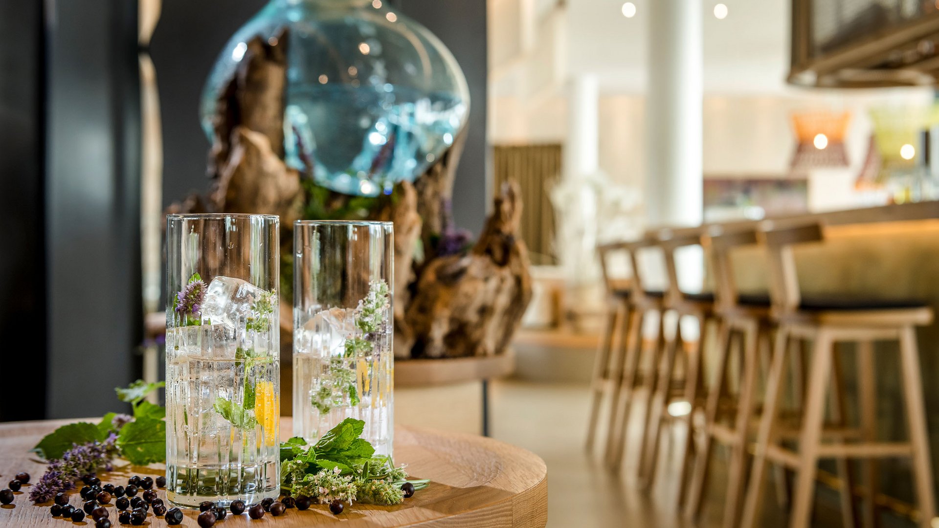 Two glasses with ice and herbs on a wooden table in a bar