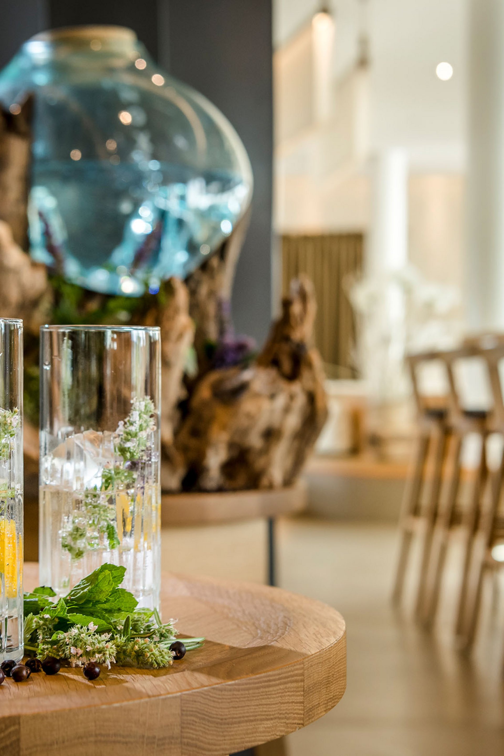 Two glasses with ice and herbs on a wooden table in a bar