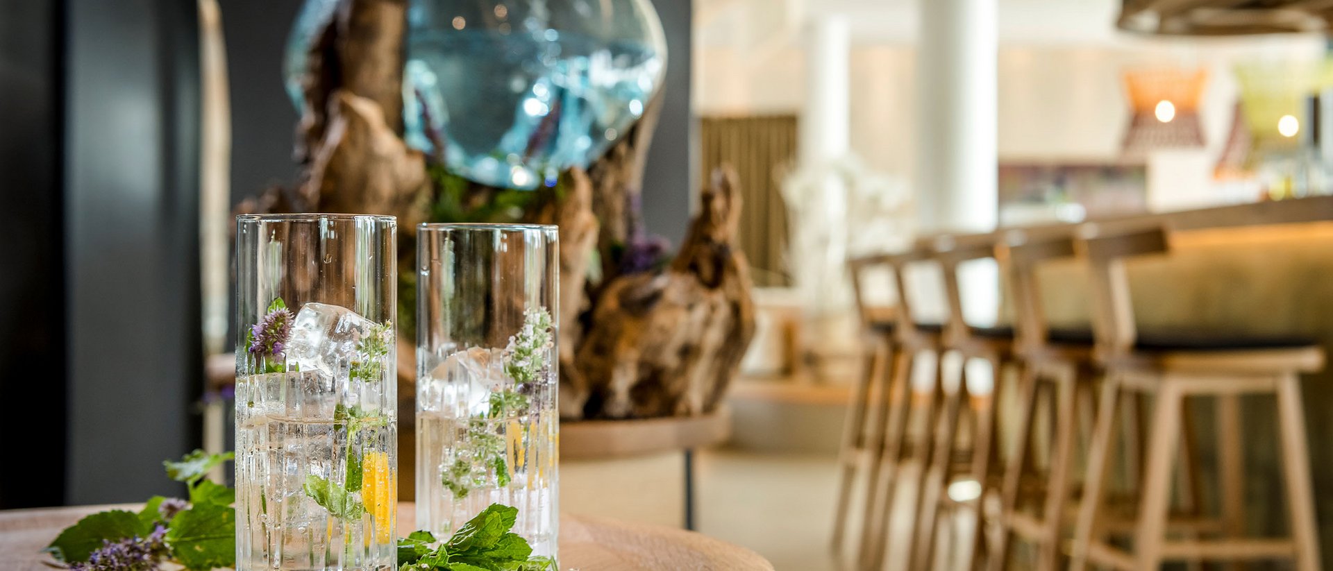 Two glasses with ice and herbs on a wooden table in a bar