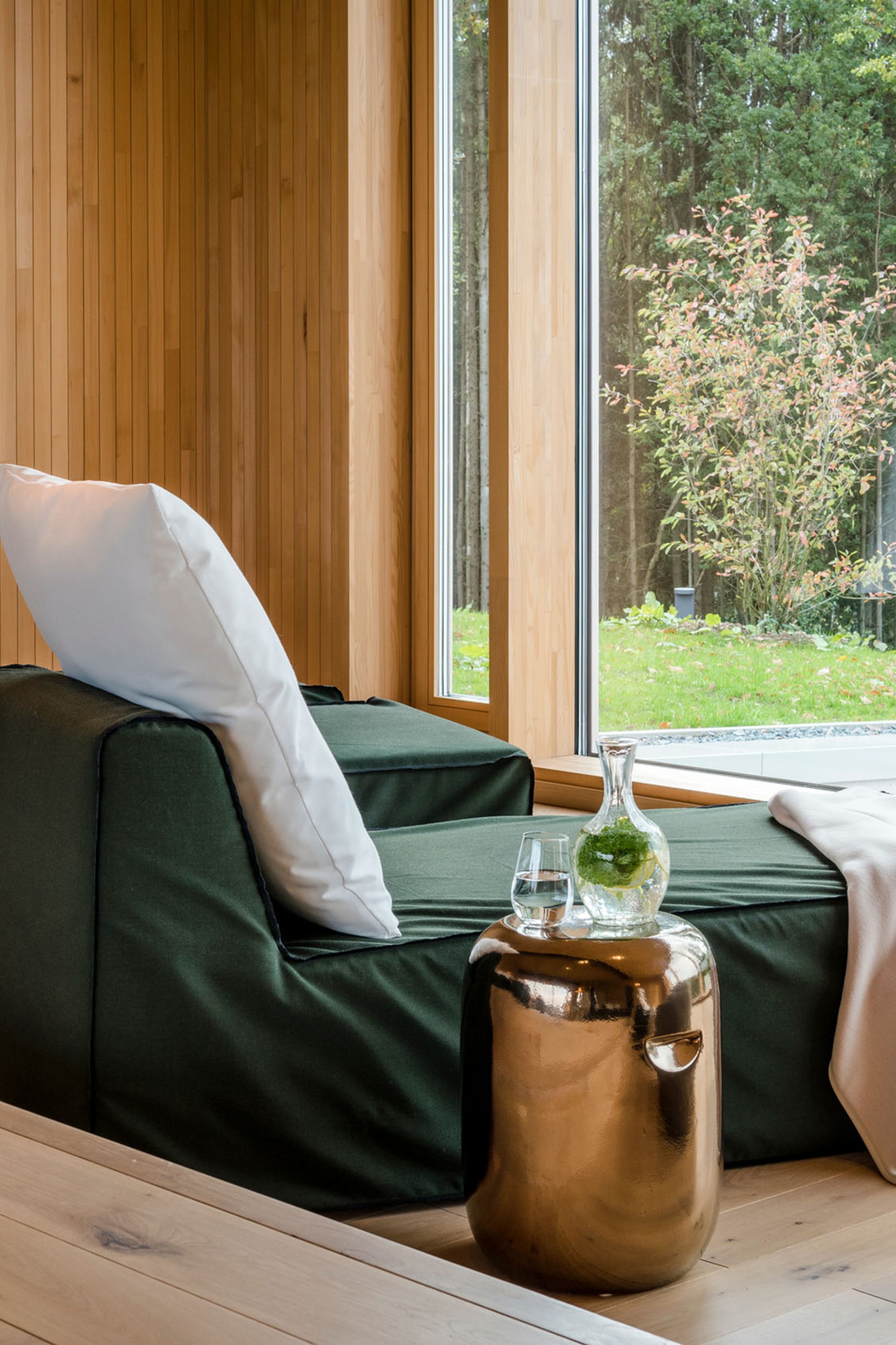 Entspannungsbereich mit Liegestuhl, Kissen, Decke und grünem Ausblick