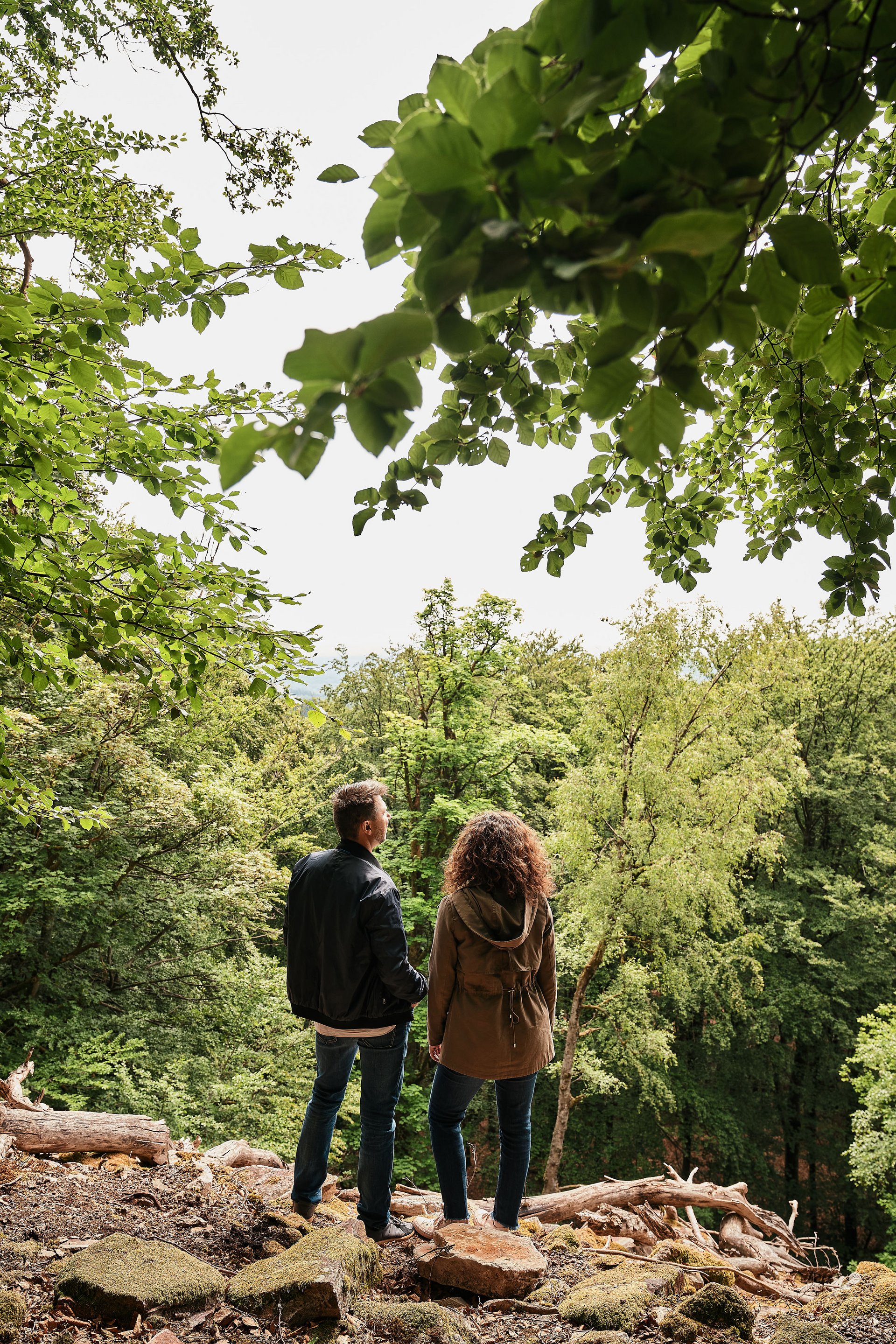 Paar steht im Wald und blickt auf Bäume und Natur