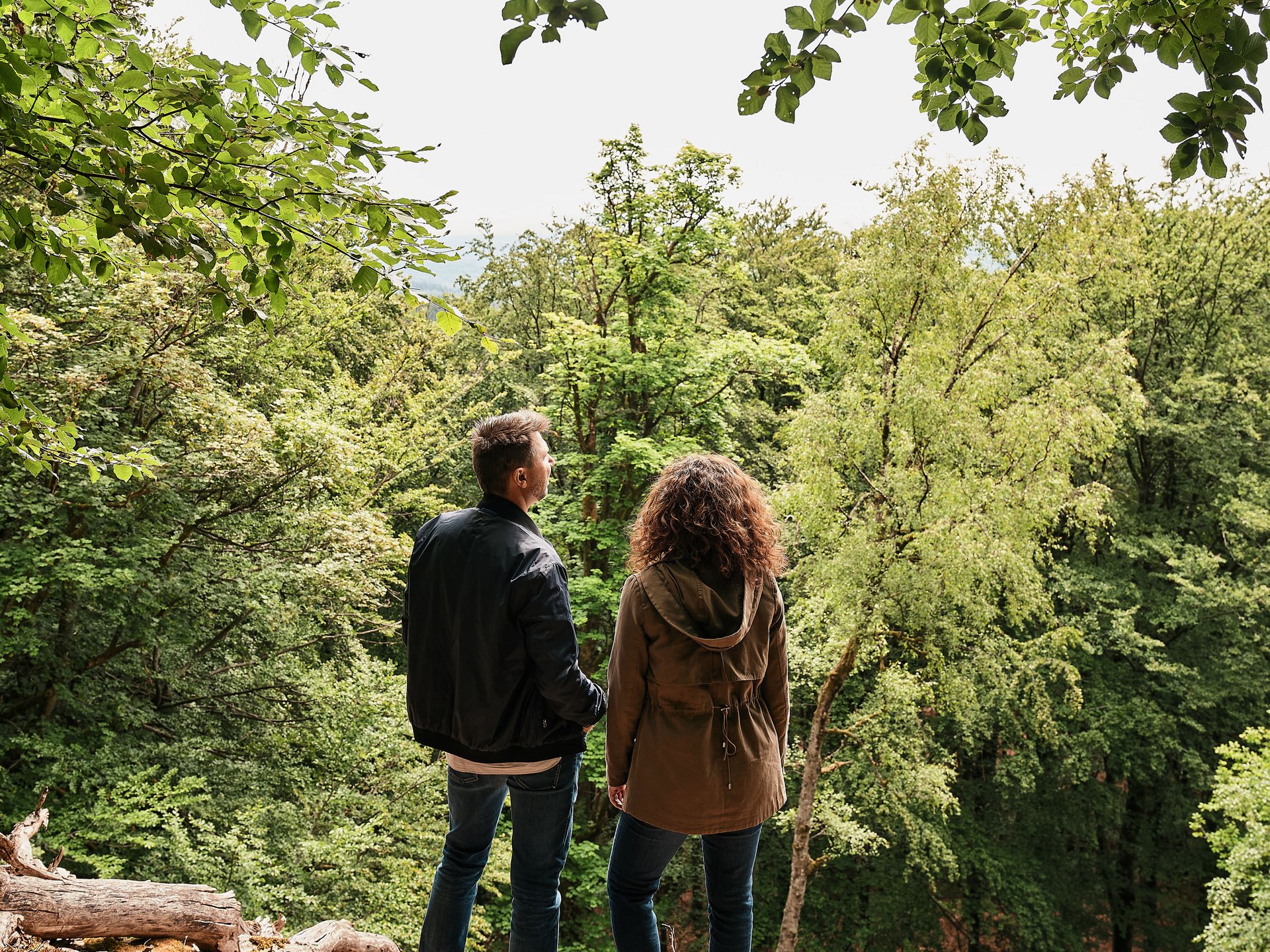 Paar steht im Wald und blickt auf Bäume und Natur