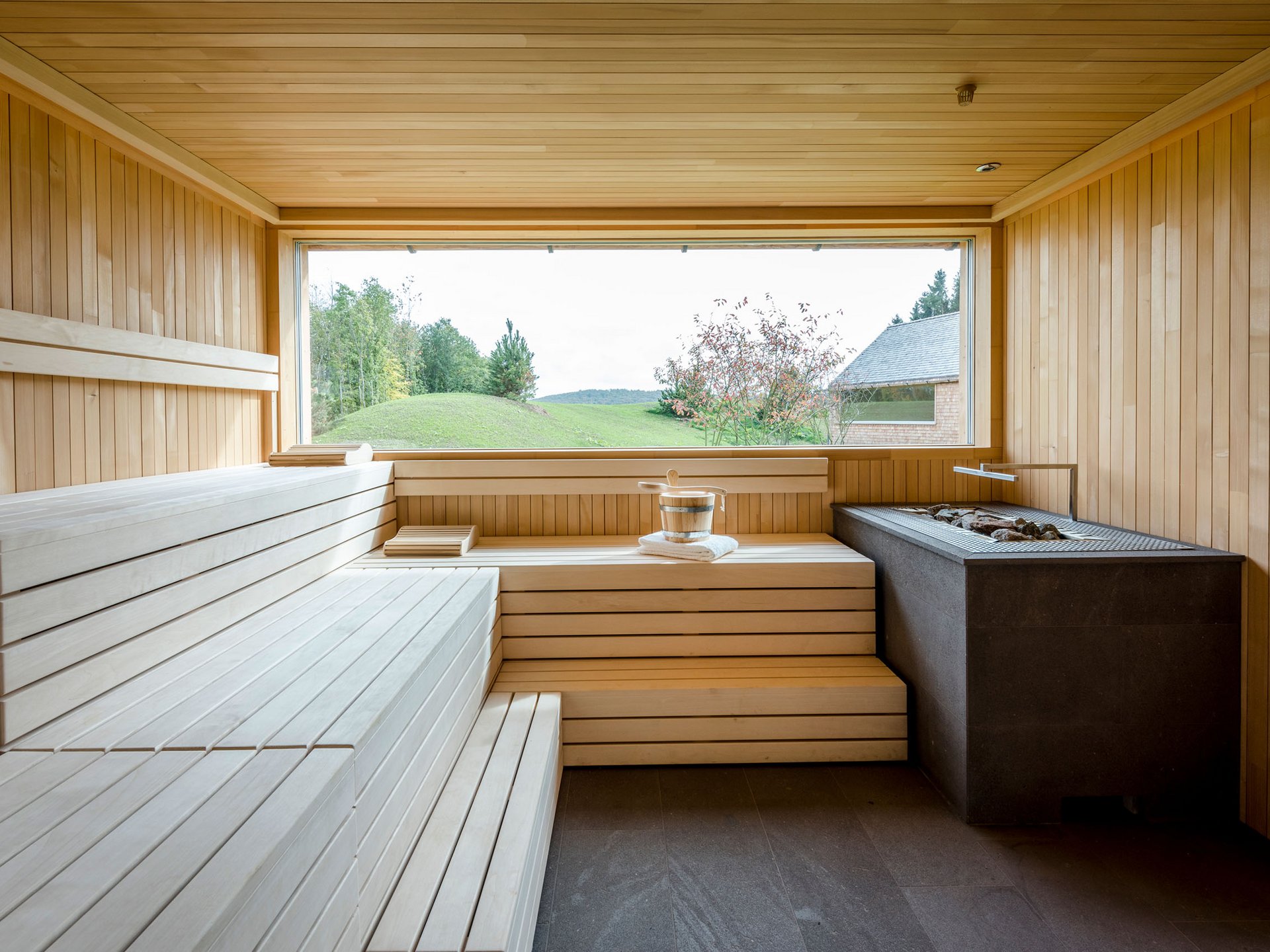 Salle de sauna en bois moderne avec grande fenêtre donnant sur paysage