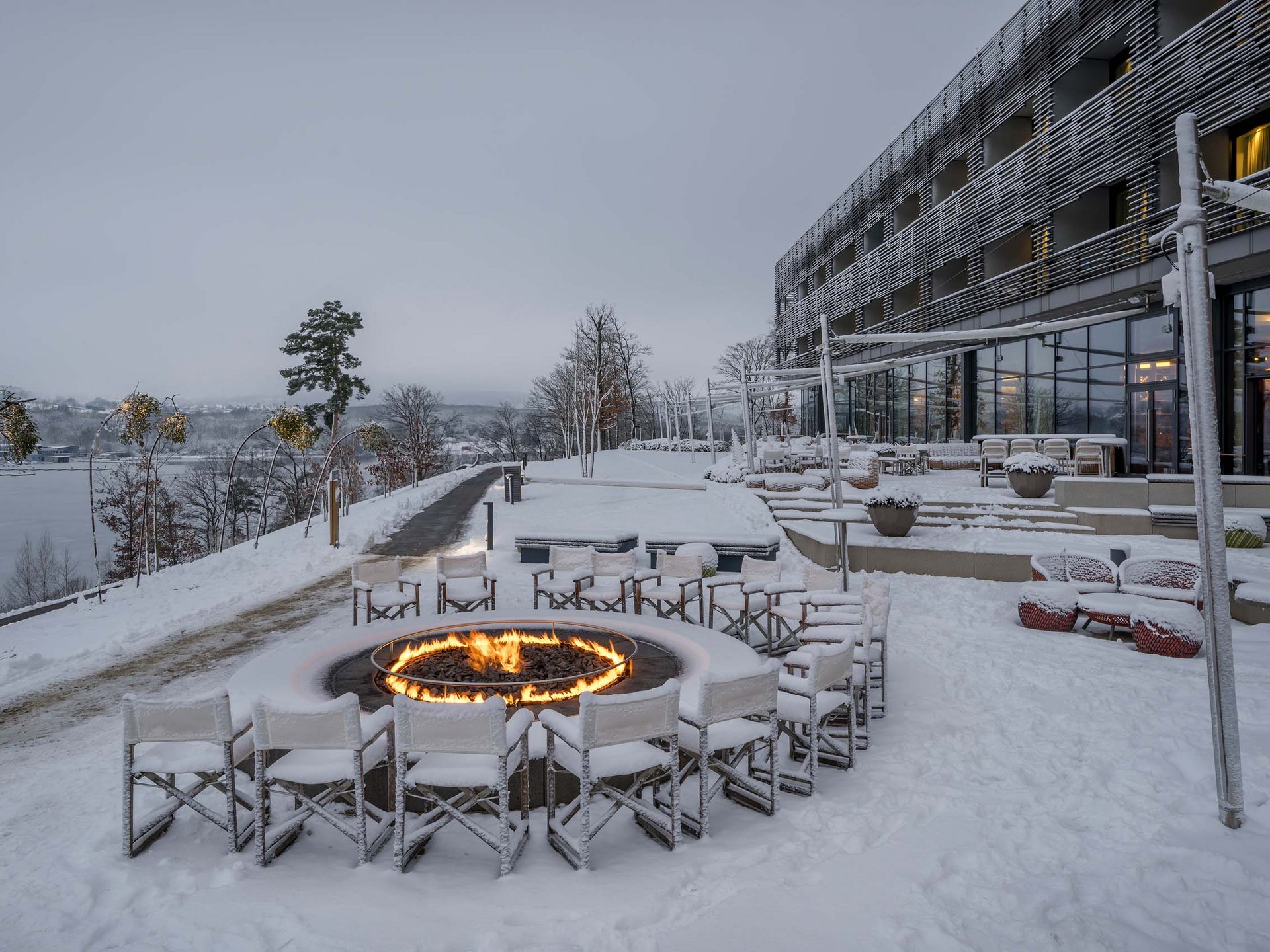 Verschneite Hotelterrasse mit Sitzgruppen und brennender Feuerschale