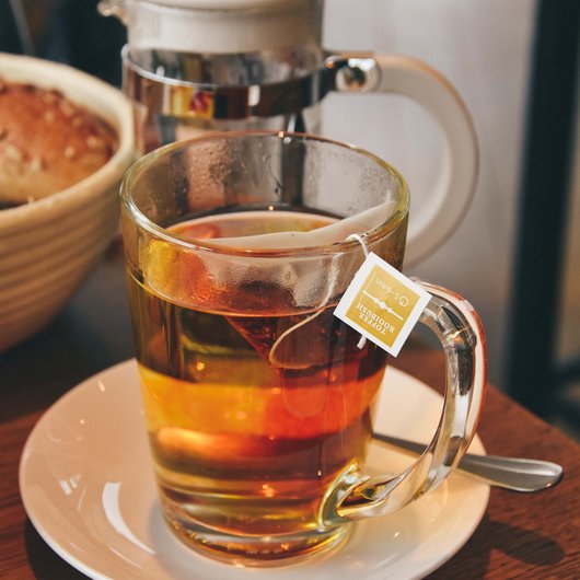 Cup of hot tea with tea bag on white saucer with spoon