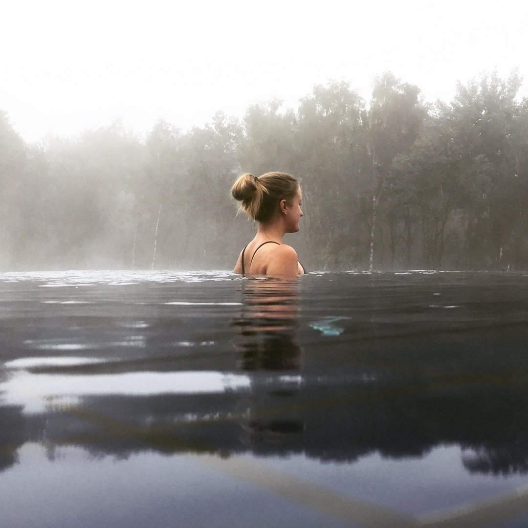 Frau entspannt im Wasser mit Nebel und Bäumen im Hintergrund
