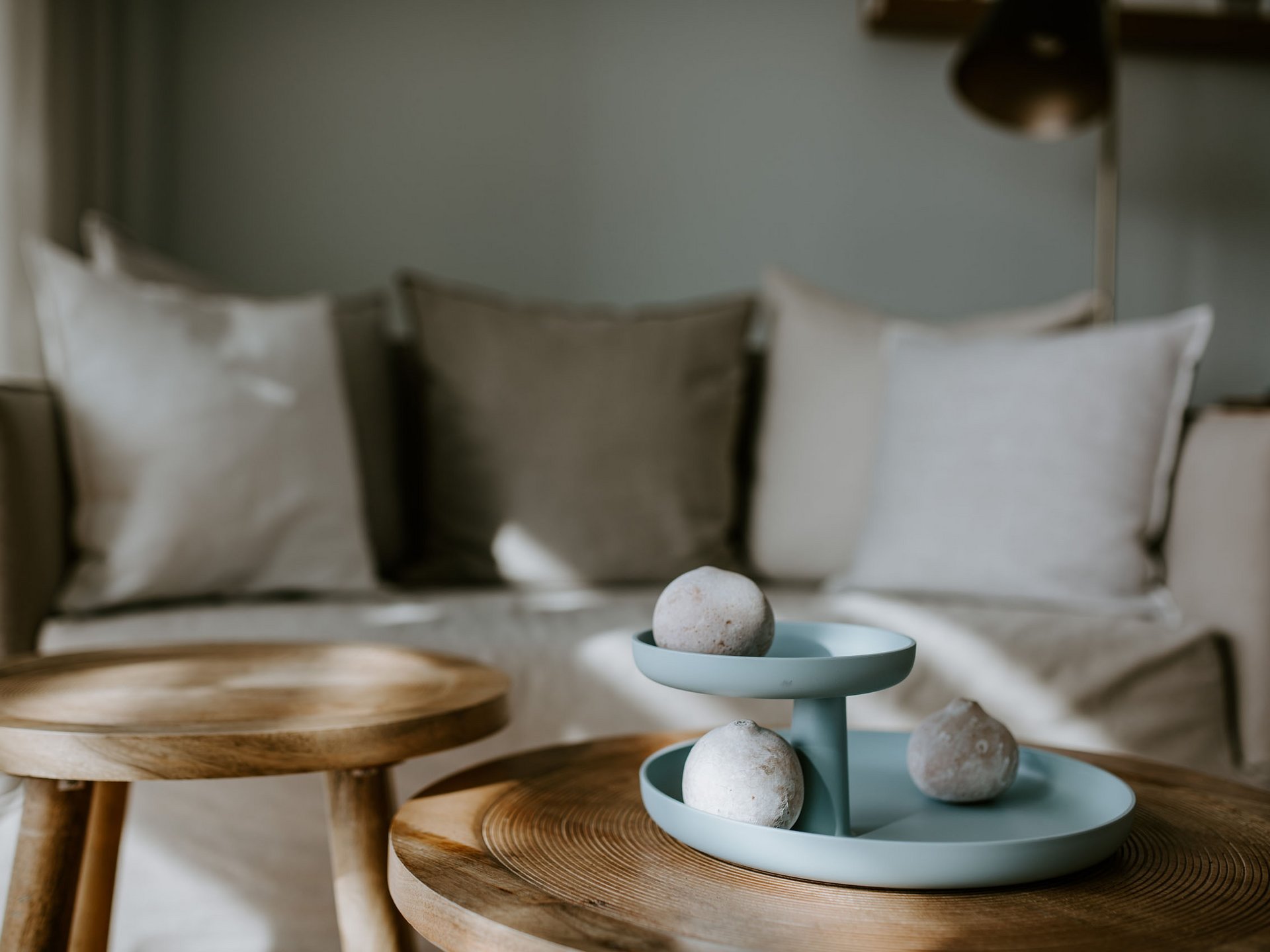 Blaues Tablett mit Dekosteinen auf Holztisch im Wohnzimmer vor Sofa