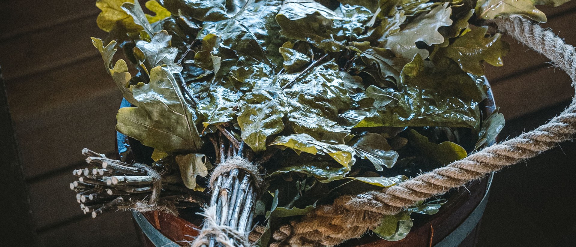 Wooden bucket with fresh oak leaf bundles in a sauna room