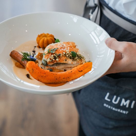 Person holding plate with gourmet fish and pumpkin dish