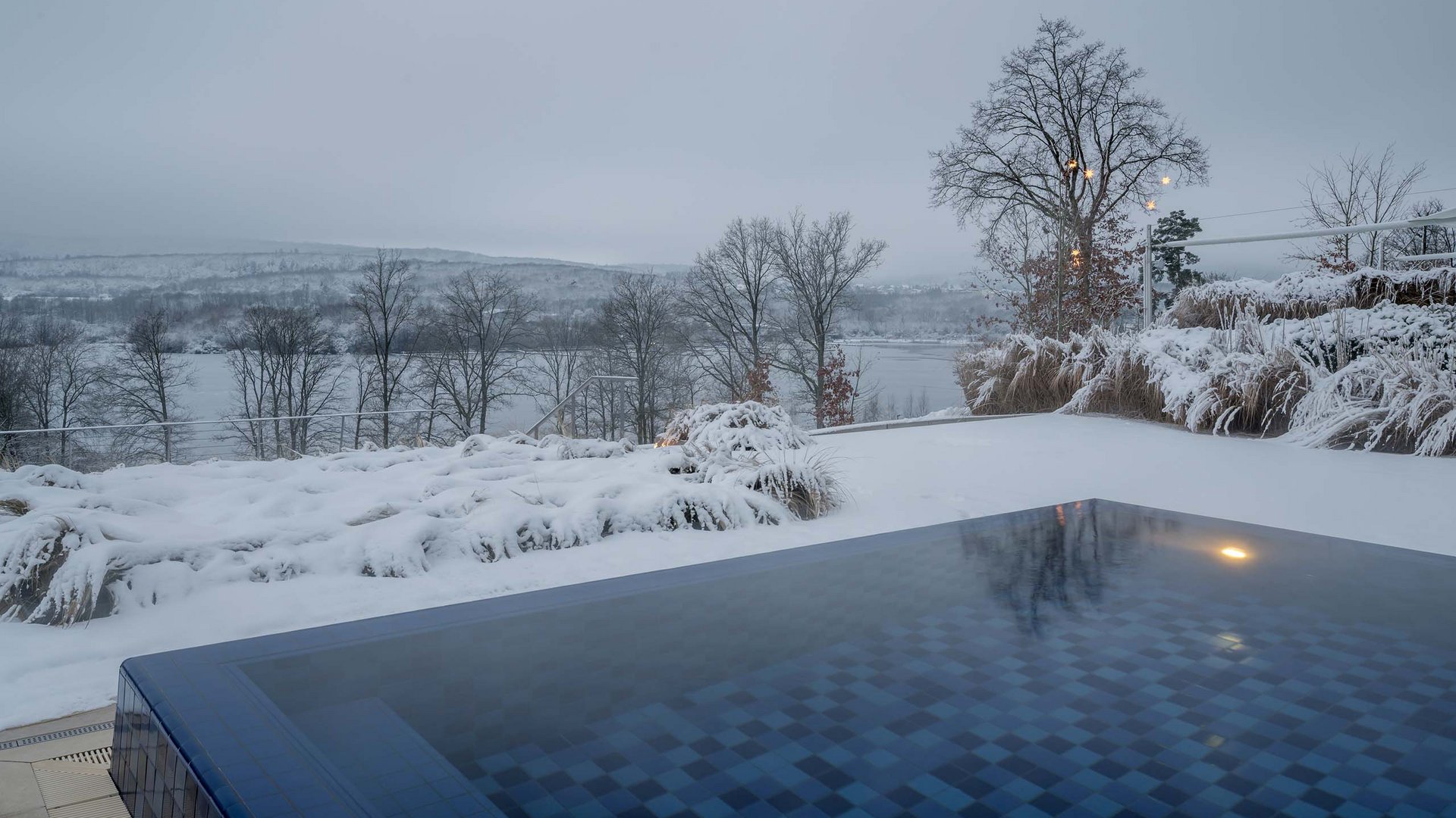 Beheizter Außenpool im verschneiten Wintergarten mit Blick auf eine winterliche Landschaft