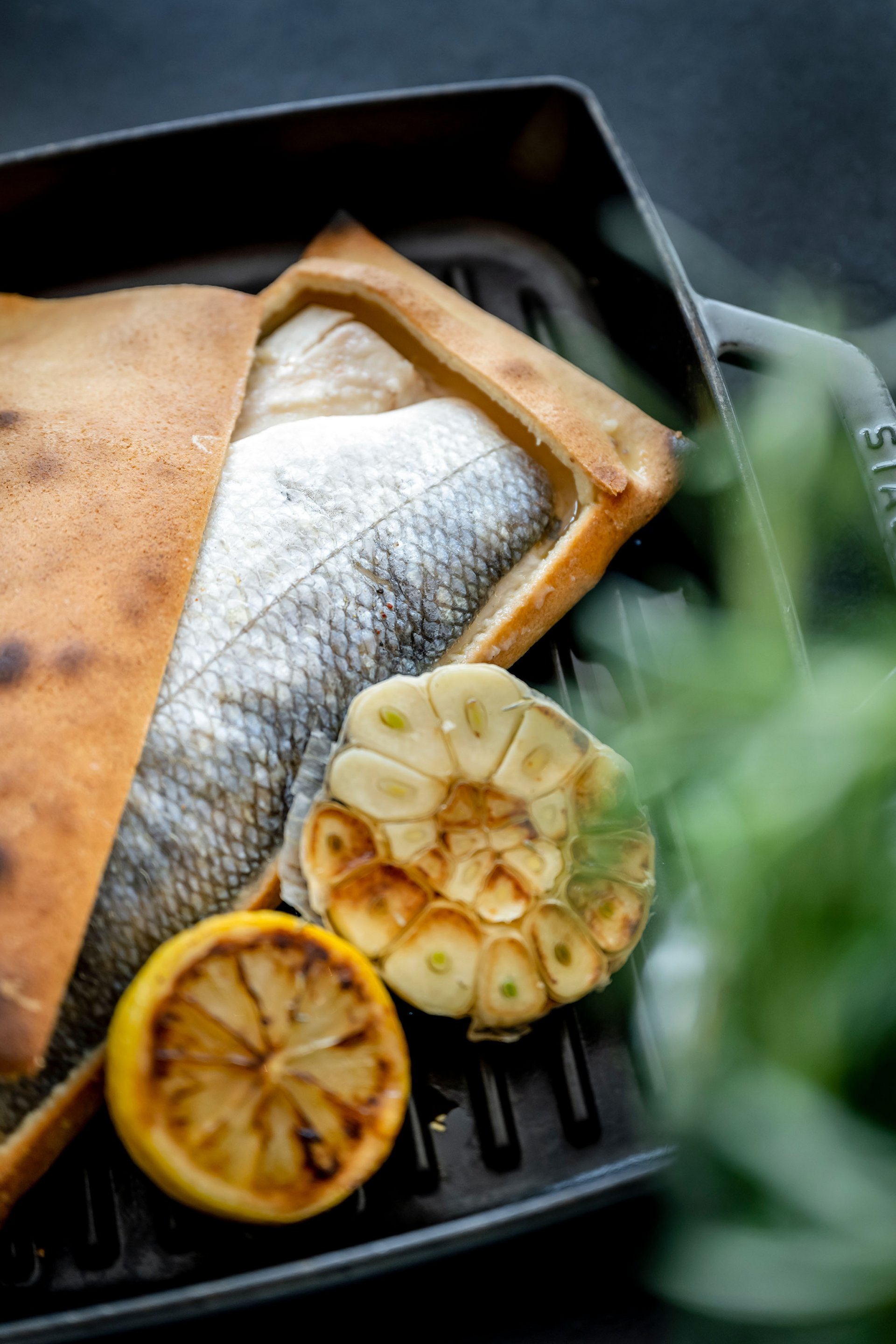 Gebackener Fisch mit geröstetem Knoblauch und Zitrone auf Grillpfanne