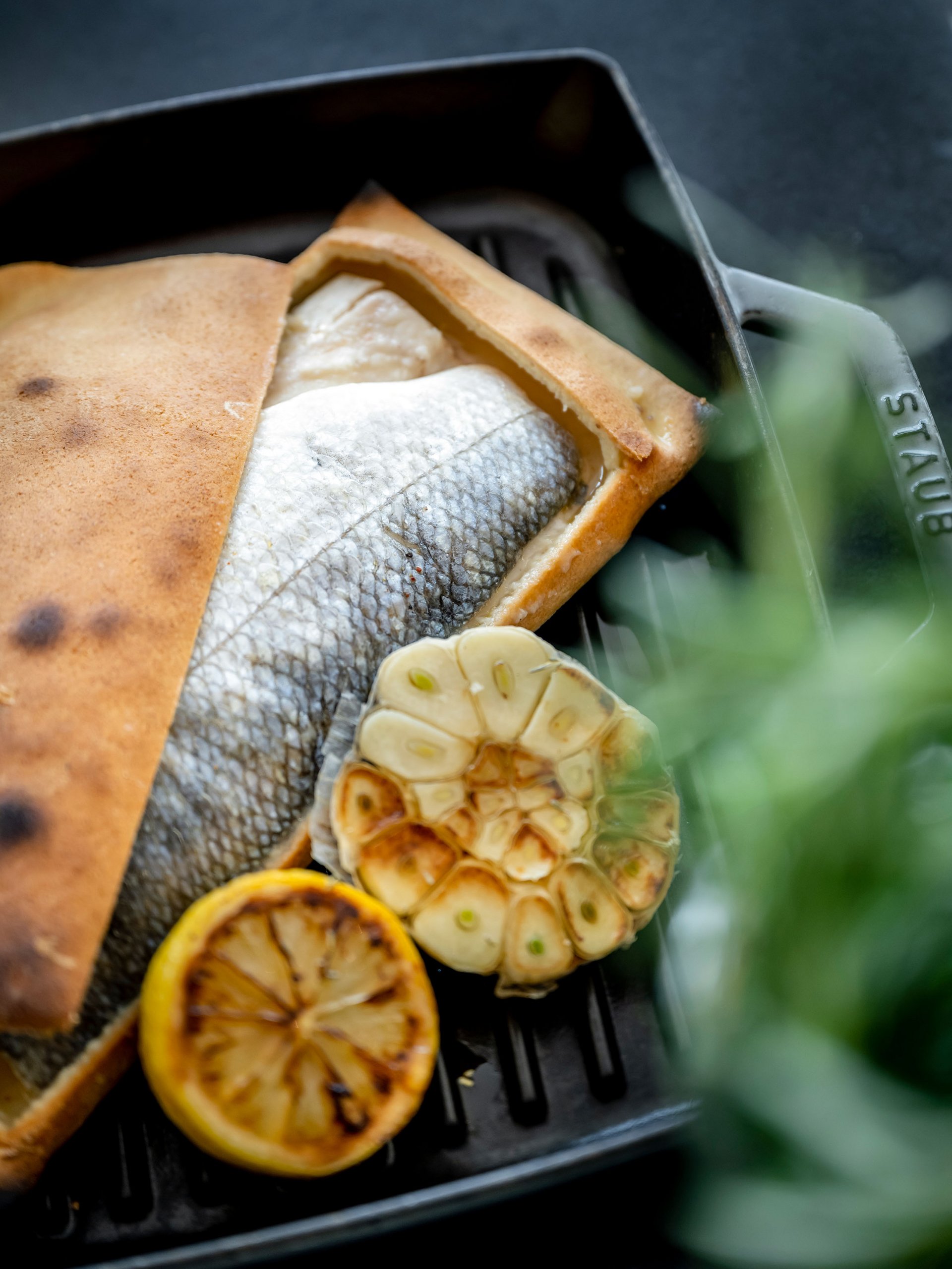 Baked fish with roasted garlic and lemon on grill pan