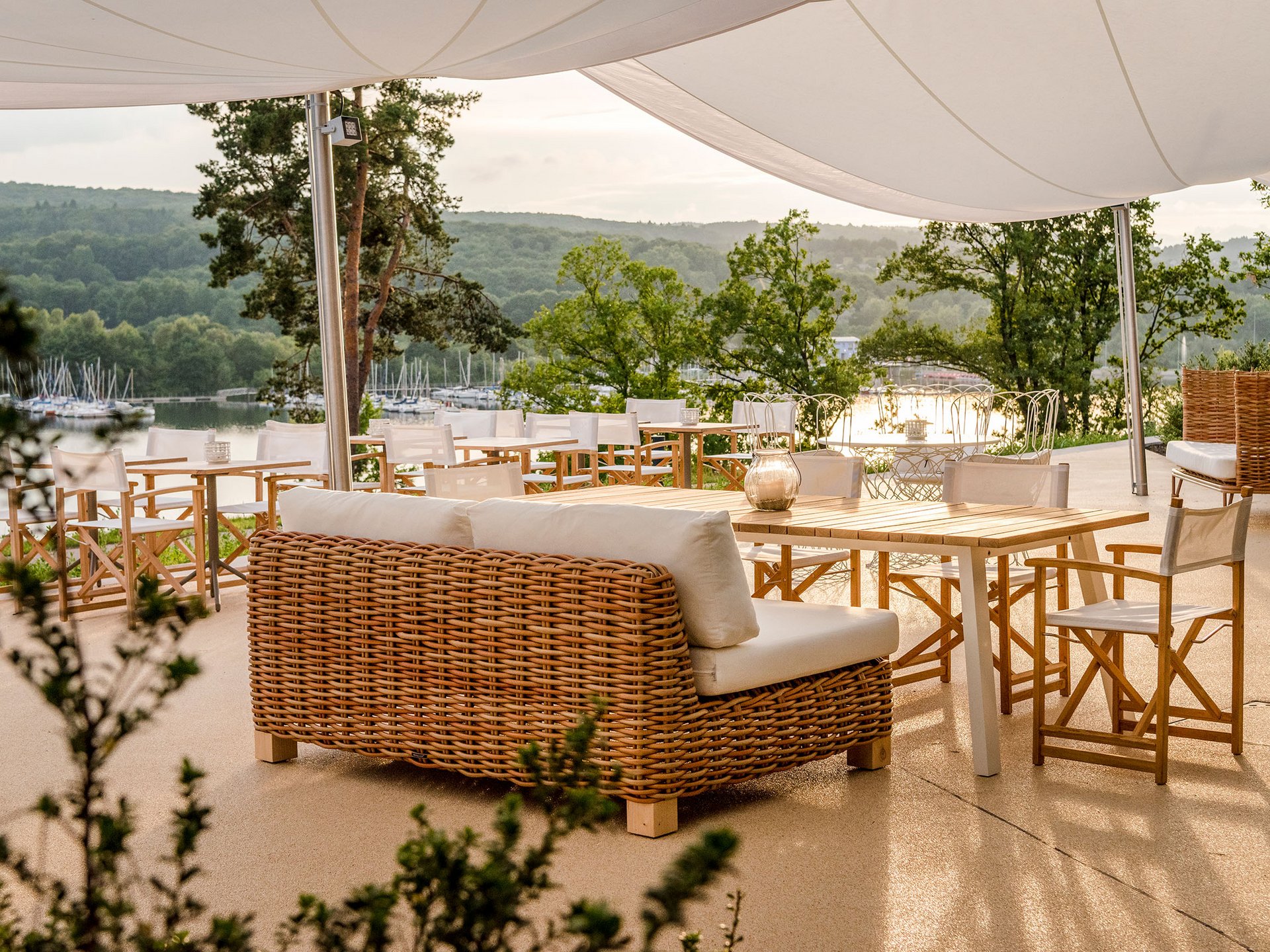 Terrace with rattan furniture overlooking a lake and green hills