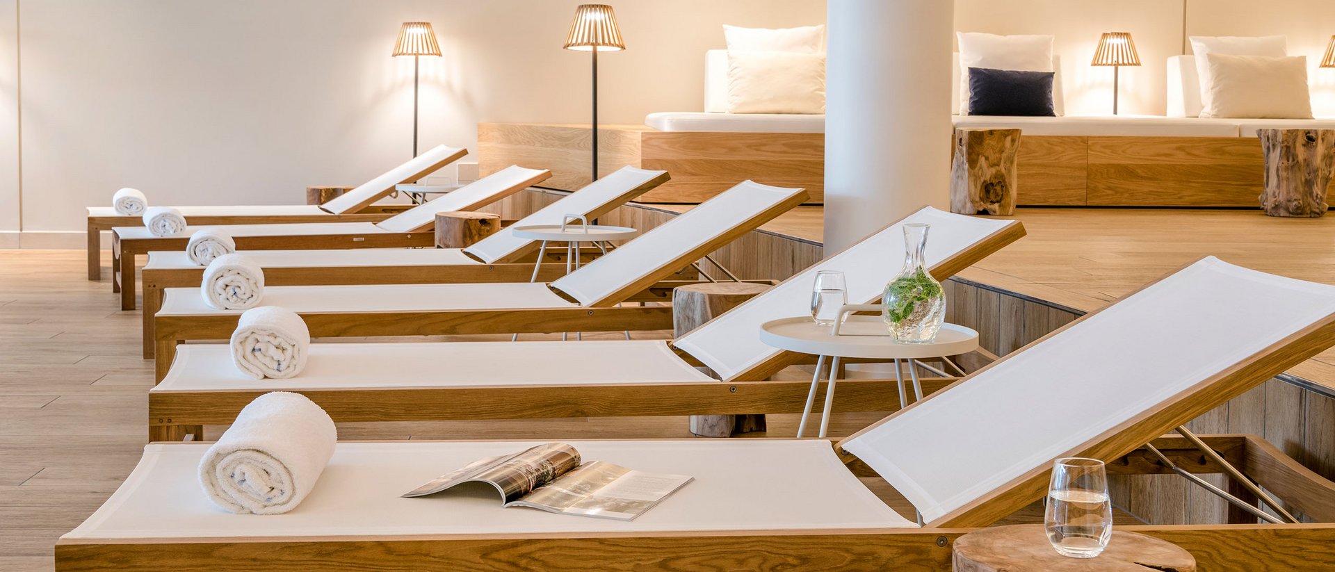 Reihe von Liegestühlen mit weißen Handtüchern und einem Magazin in einem modernen Spa
