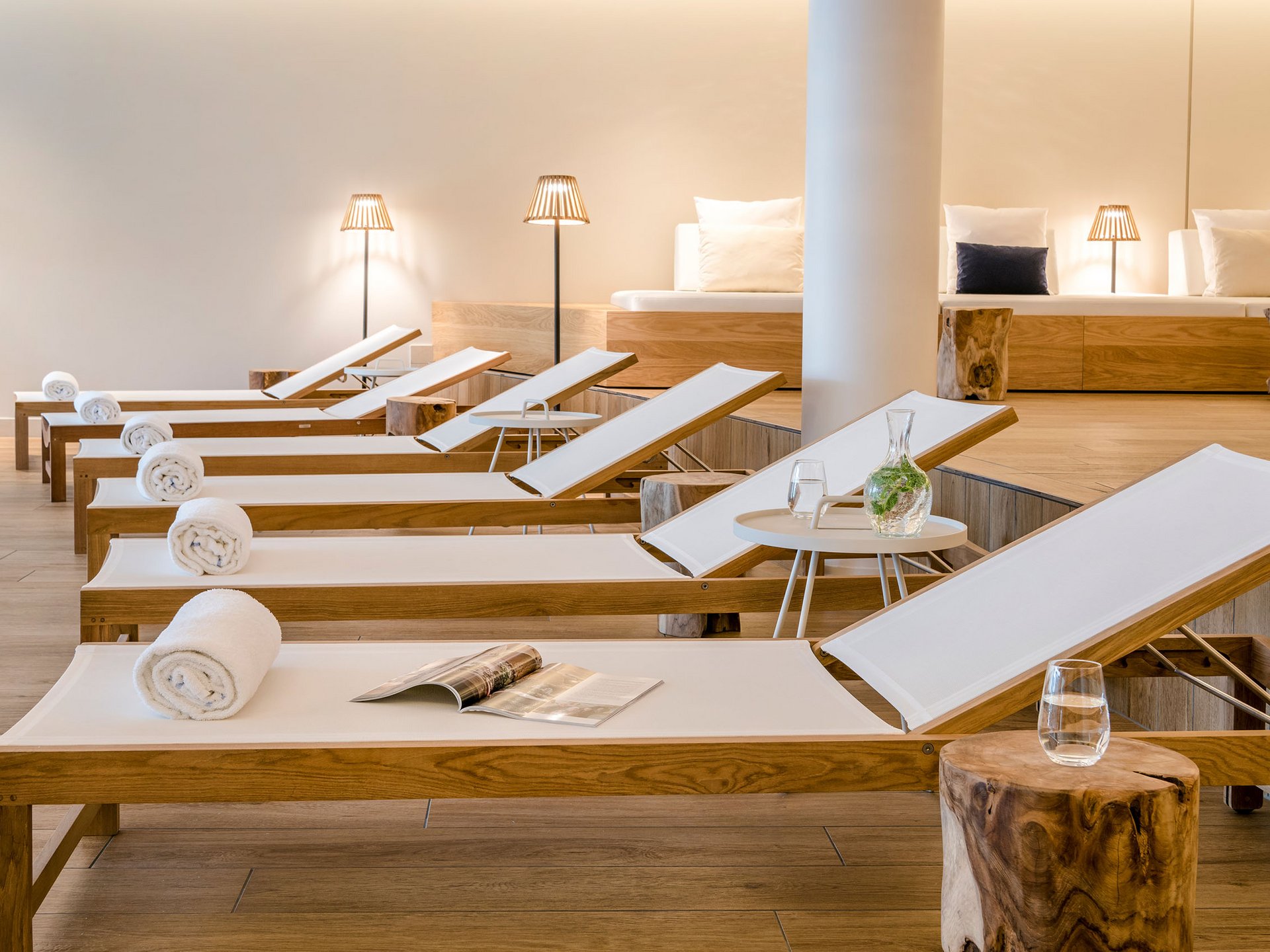 Row of lounge chairs with white towels and magazine in a modern spa