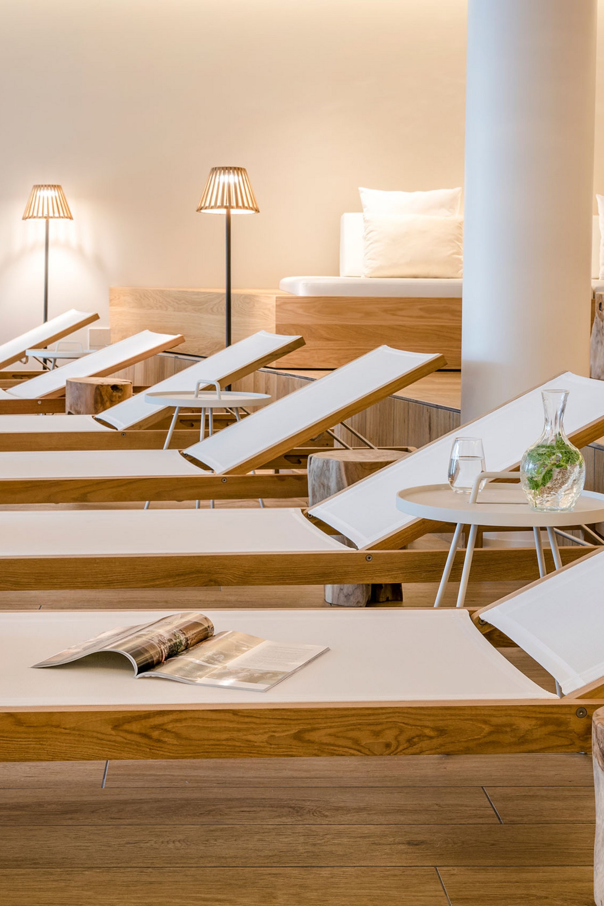 Reihe von Liegestühlen mit weißen Handtüchern und einem Magazin in einem modernen Spa