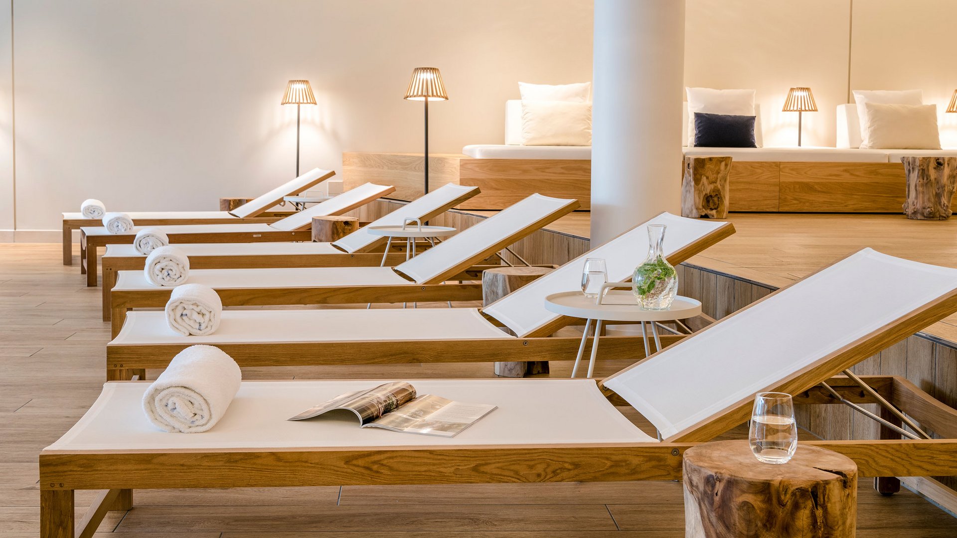 Reihe von Liegestühlen mit weißen Handtüchern und einem Magazin in einem modernen Spa