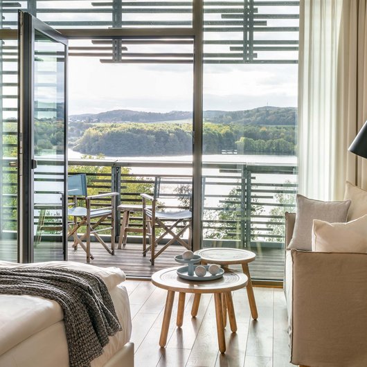 Gemütliches Hotelzimmer mit Balkon und Blick auf See und Wald