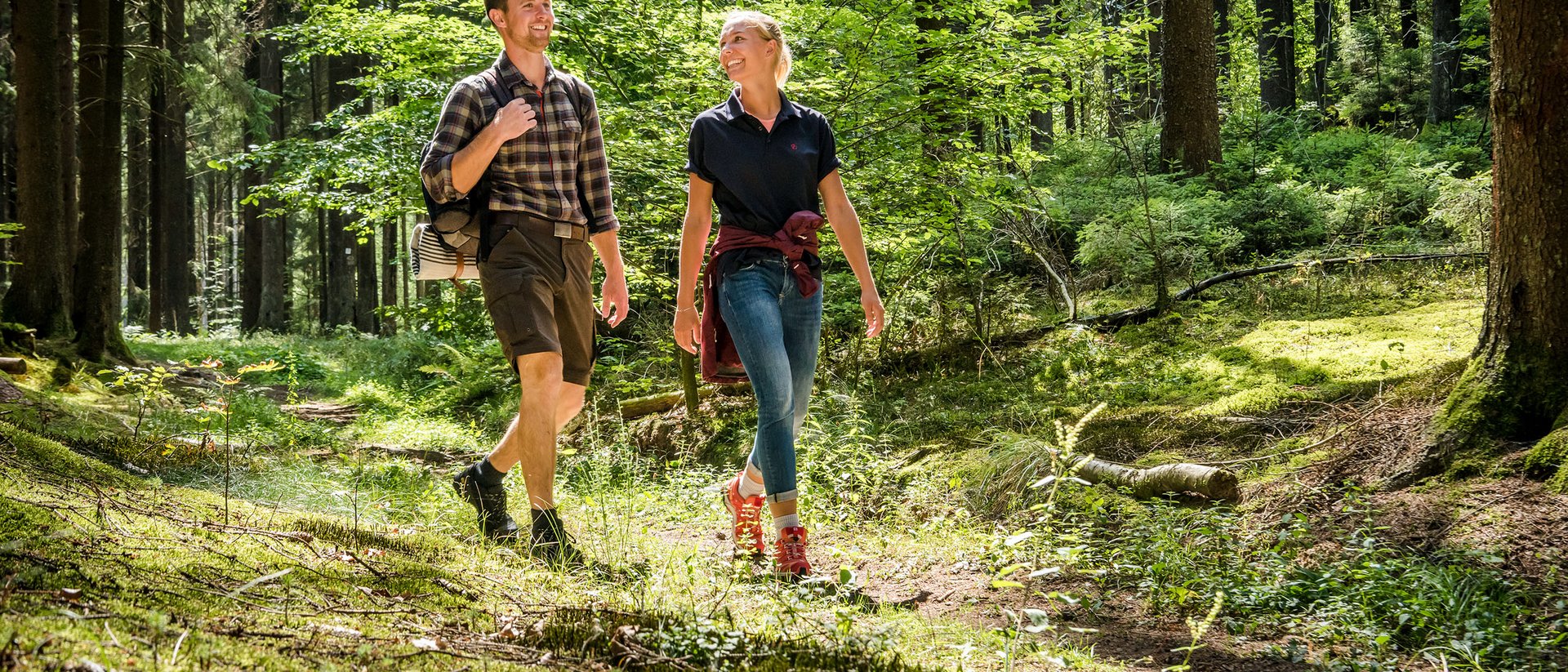 Couple marchant joyeusement sur un sentier ensoleillé en forêt