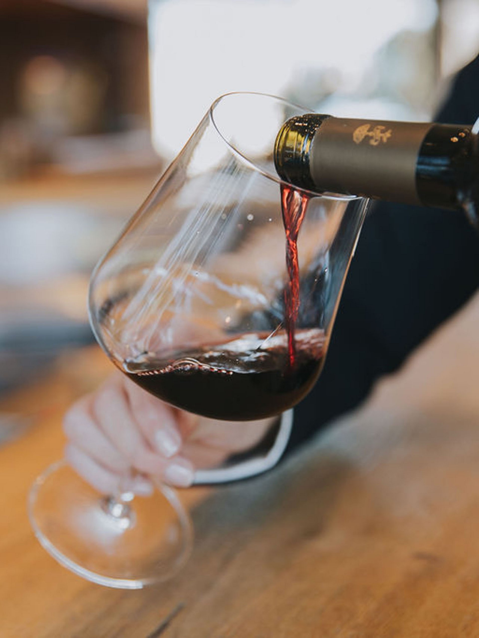 Rotwein wird in ein Glas an einer Bar eingeschenkt