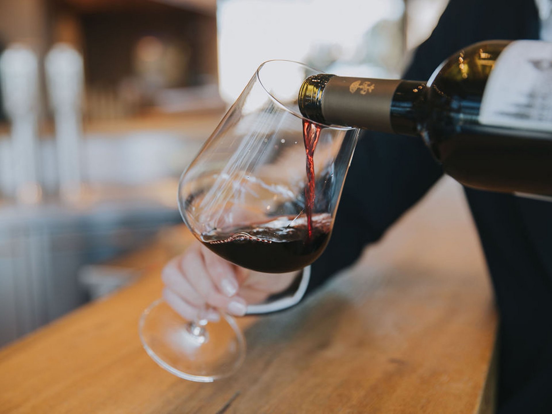 Rotwein wird in ein Glas an einer Bar eingeschenkt