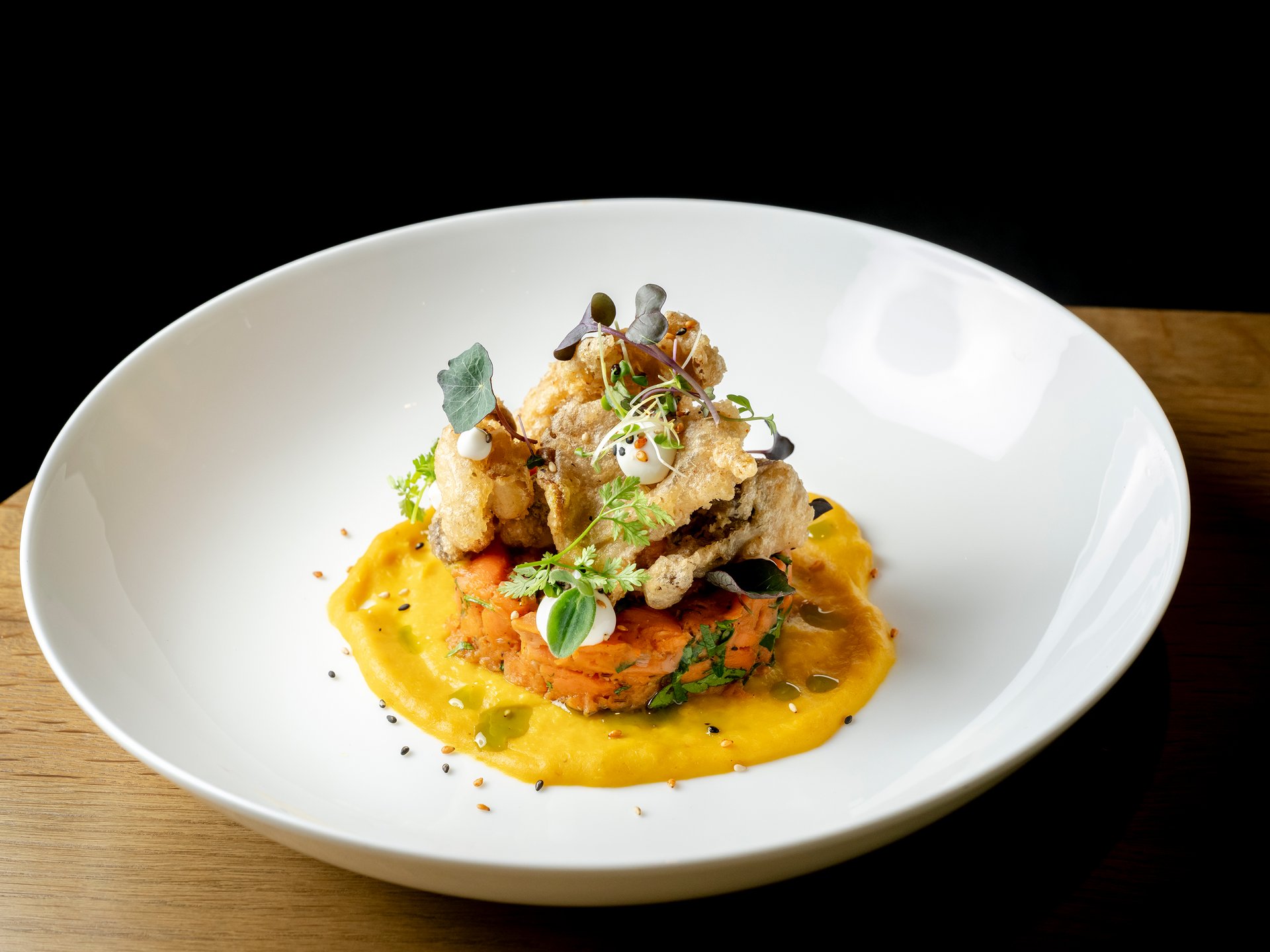 Kreatives Gourmetgericht mit Gemüsepüree und knusprigen Garnierungen auf weißem Teller