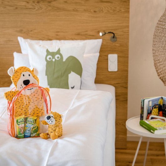 Chambre d'enfant avec peluches, livres et lit avec linge de lit blanc