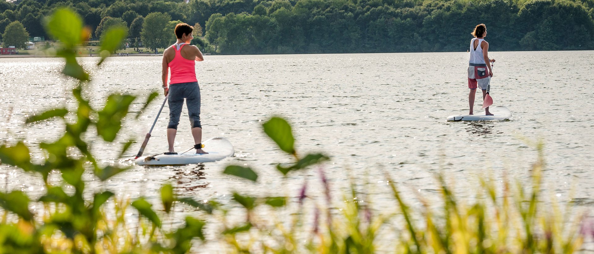 Deux femmes en paddle sur un lac entouré de forêt