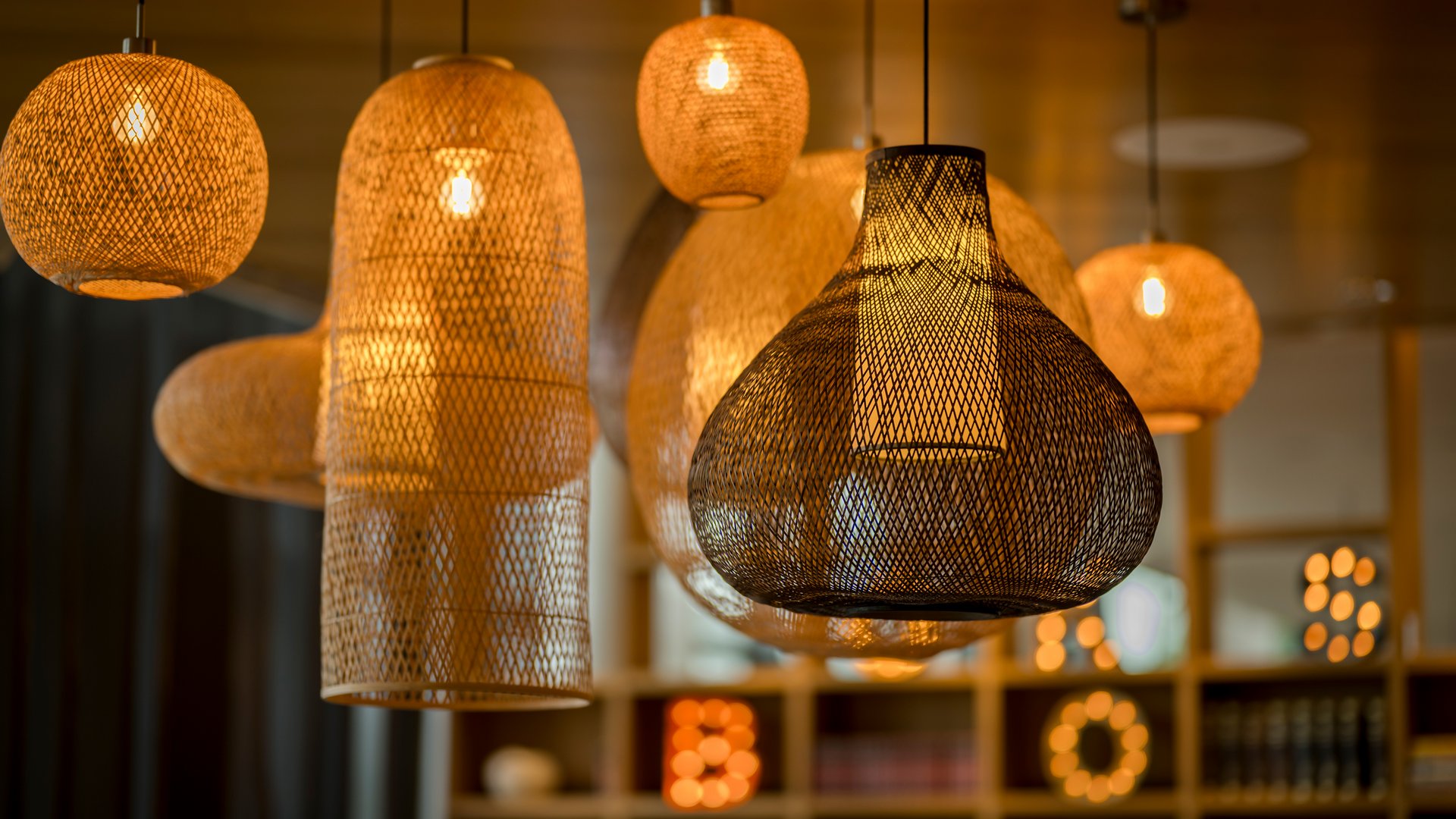 Différents luminaires suspendus en osier illuminés par une lumière chaude