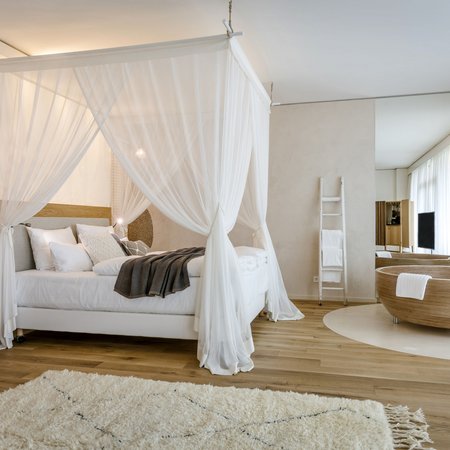 Modernes Schlafzimmer mit Himmelbett und freistehender Badewanne in hellem Ambiente