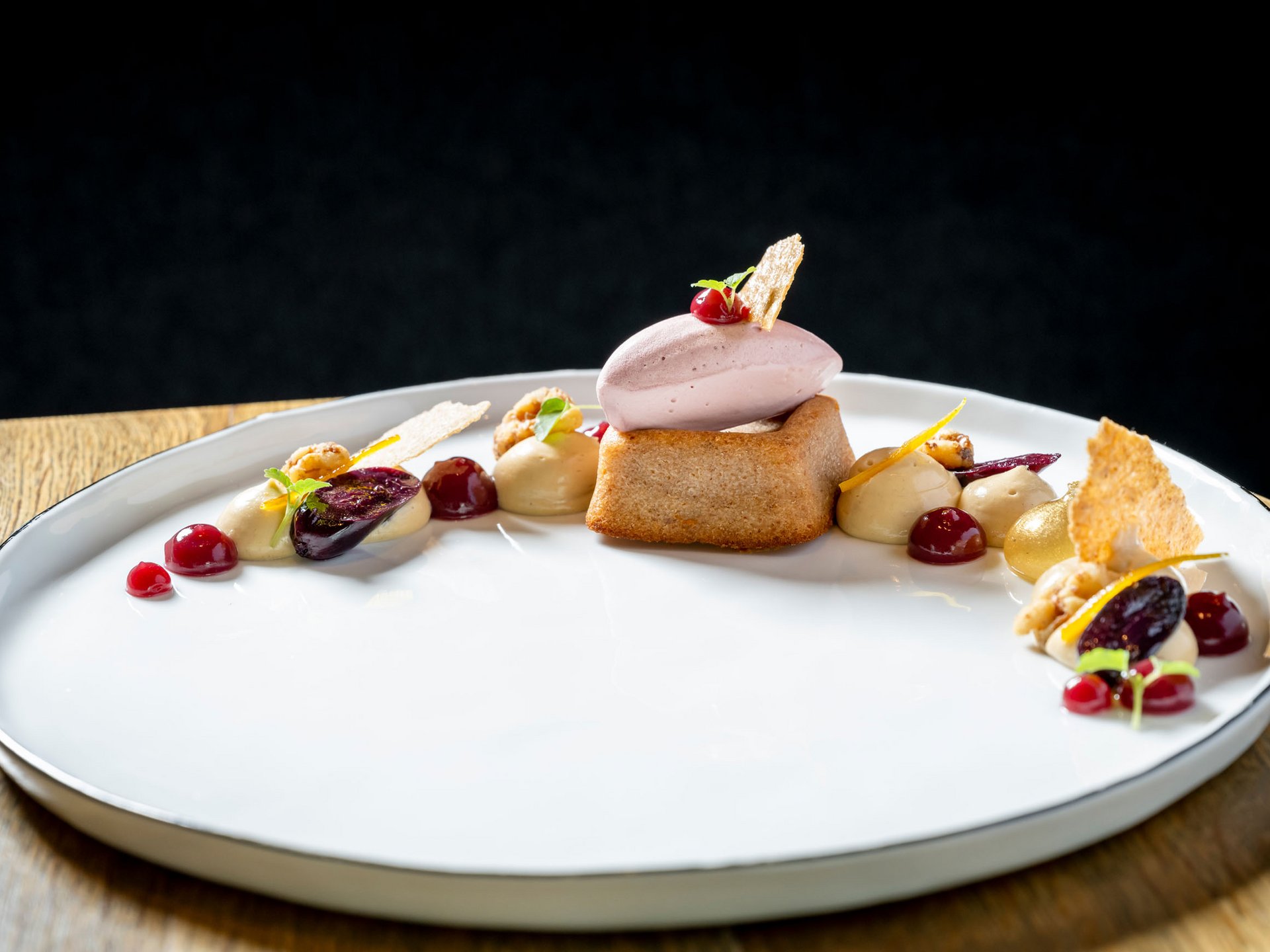 Elegant dessert with sponge cake, ice cream and fruit sauces on white plate