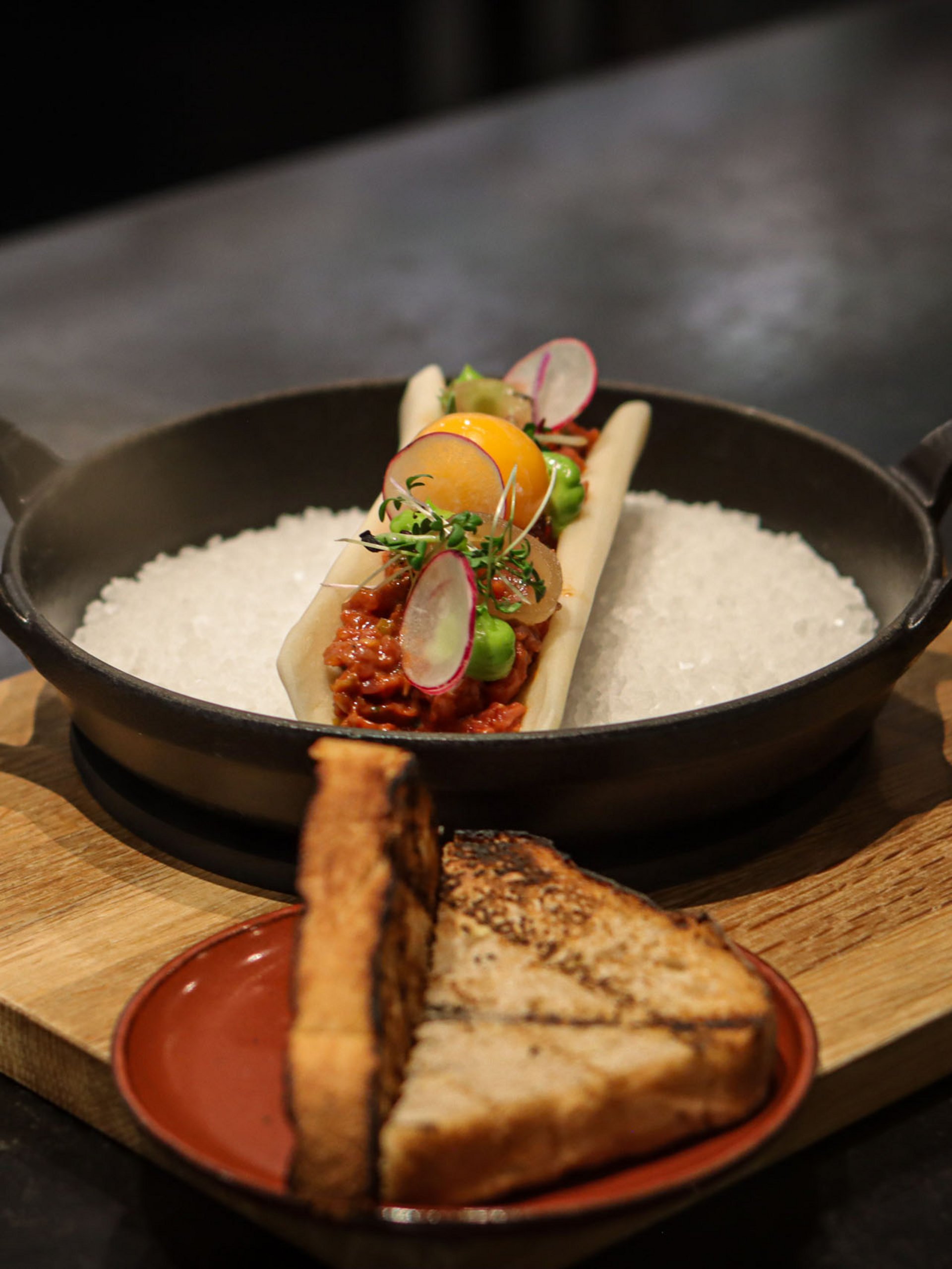 Garnished gourmet dish with toast served on wooden boards