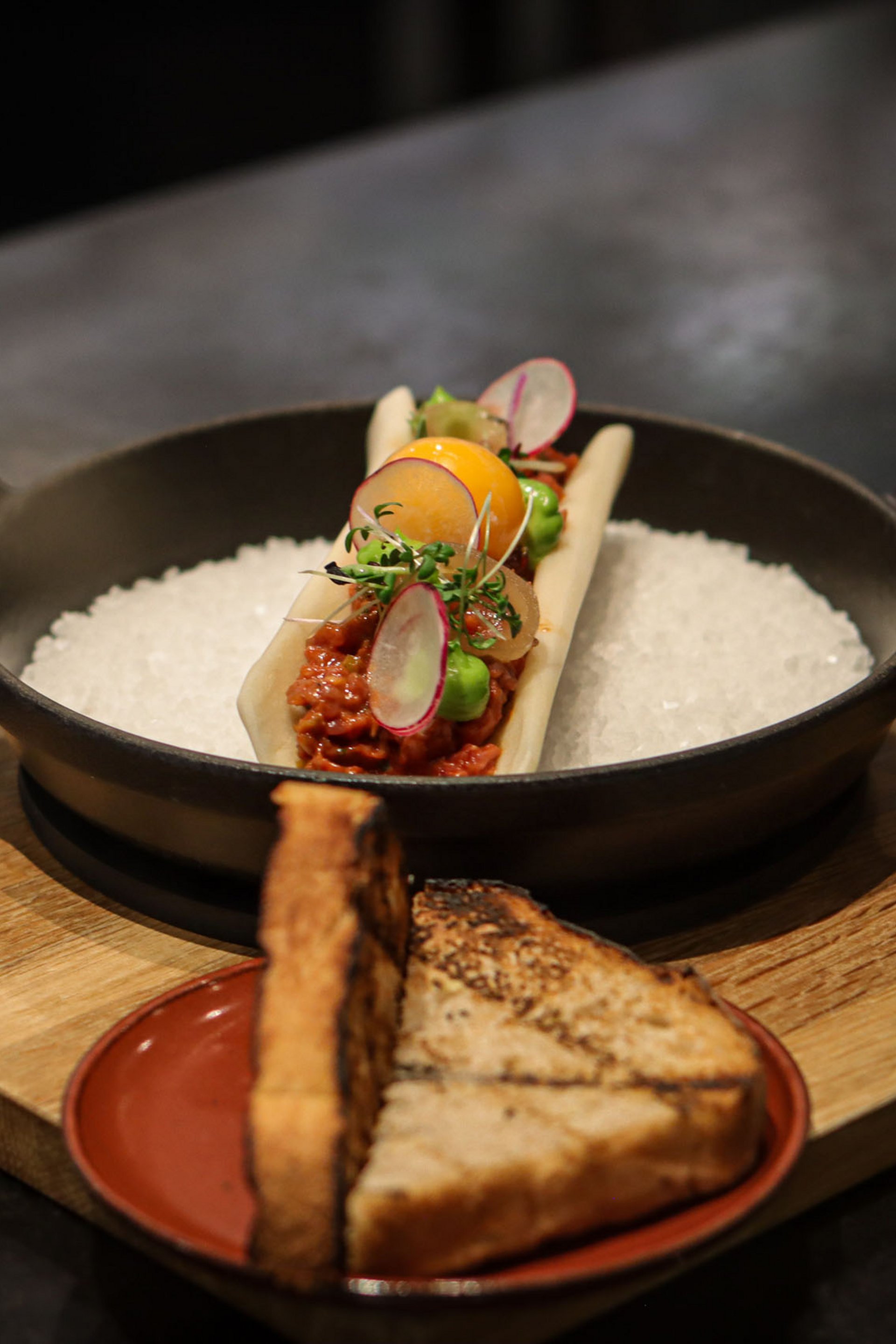 Garnished gourmet dish with toast served on wooden boards