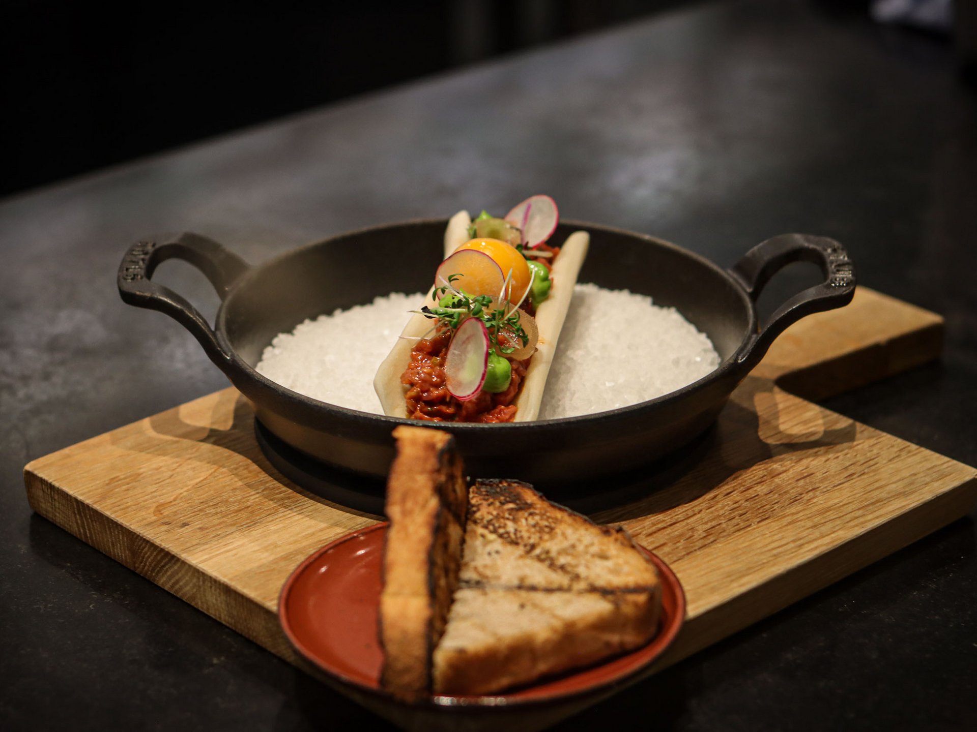 Garnished gourmet dish with toast served on wooden boards