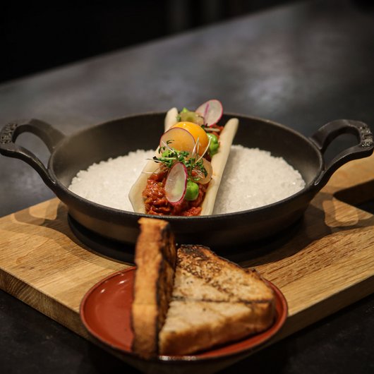 Garnished gourmet dish with toast served on wooden boards