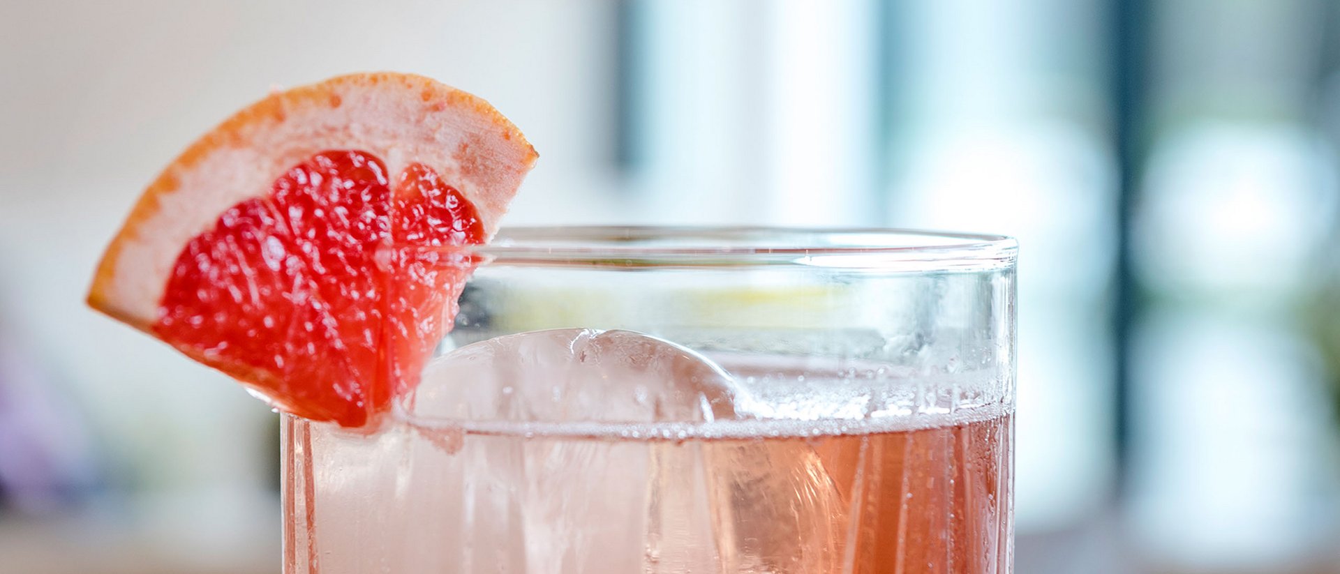 Cocktail mit Eis und Grapefruitecke auf Holzoberfläche