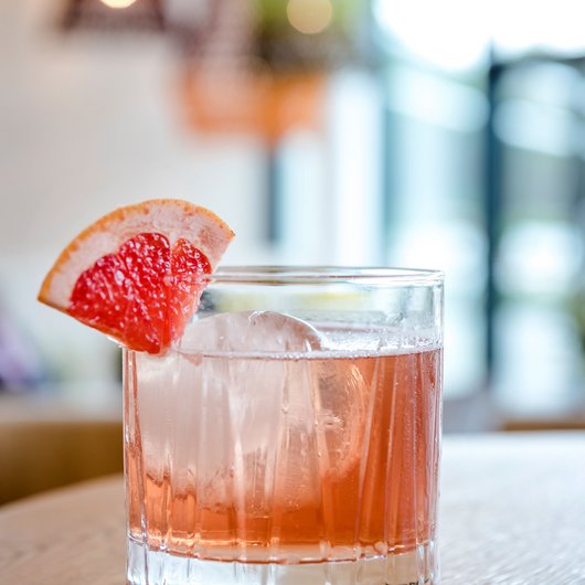 Cocktail mit Eis und Grapefruitecke auf Holzoberfläche