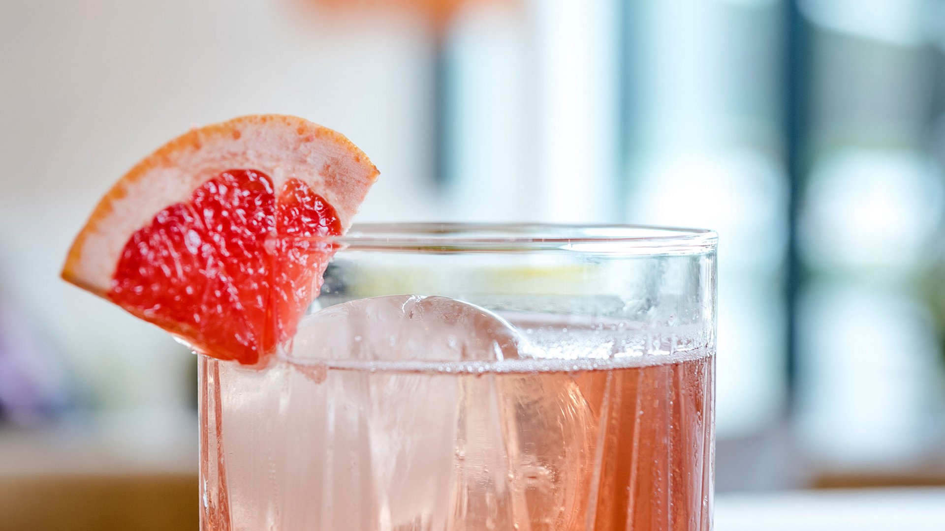 Cocktail mit Eis und Grapefruitecke auf Holzoberfläche