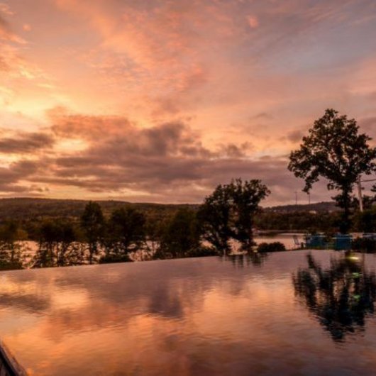 Infinity pool at sunset with reflections and trees in the background