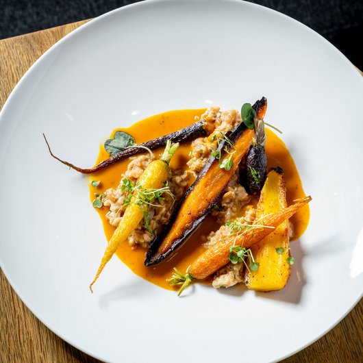 Roasted colorful carrots with sauce on a white plate