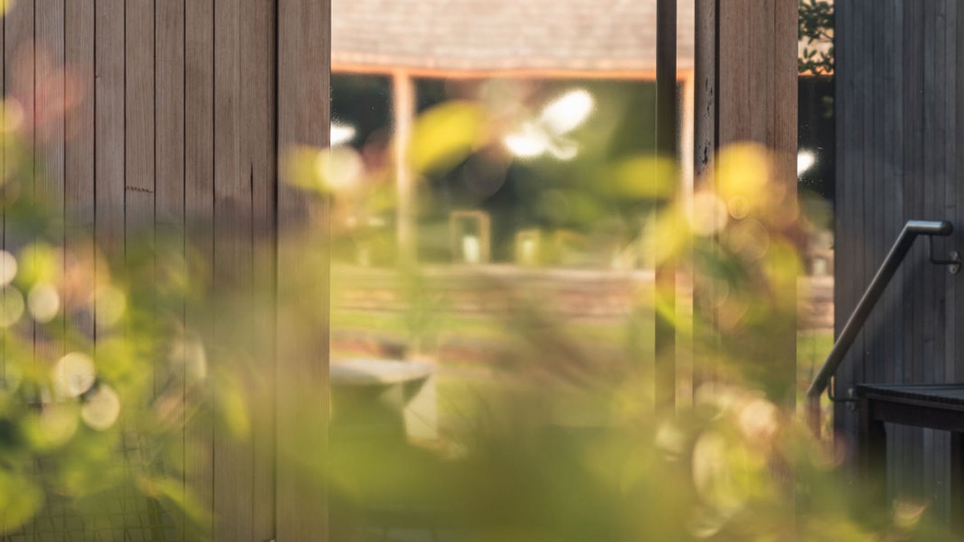 Glastür mit Aufschrift Kelten Sauna und Holzwand mit verschwommenen Pflanzen im Vordergrund