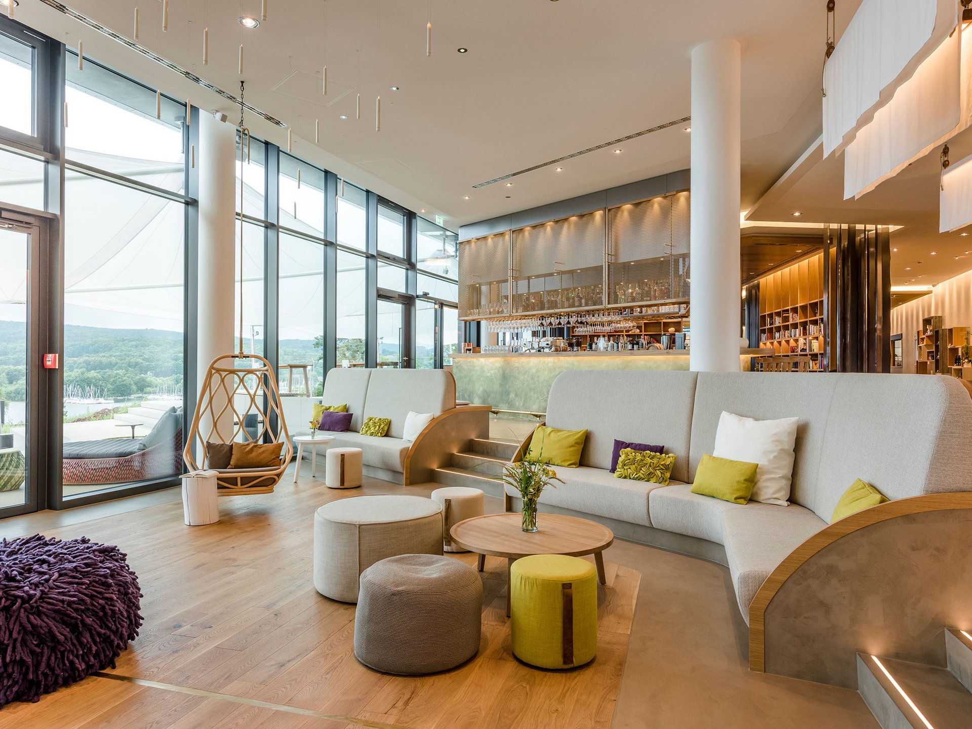 Salon moderne avec grandes fenêtres, sièges et un coin bar