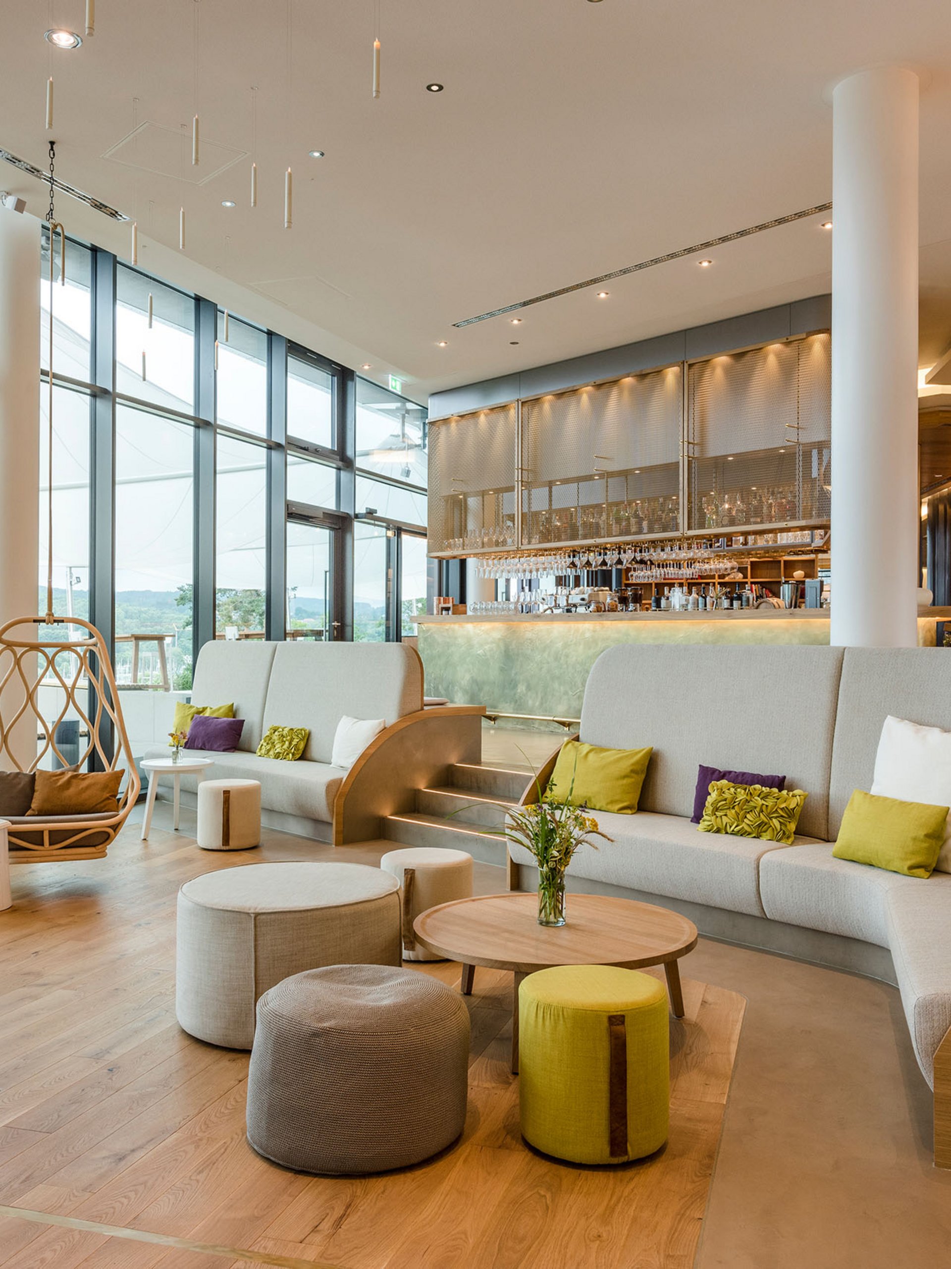 Salon moderne avec grandes fenêtres, sièges et un coin bar