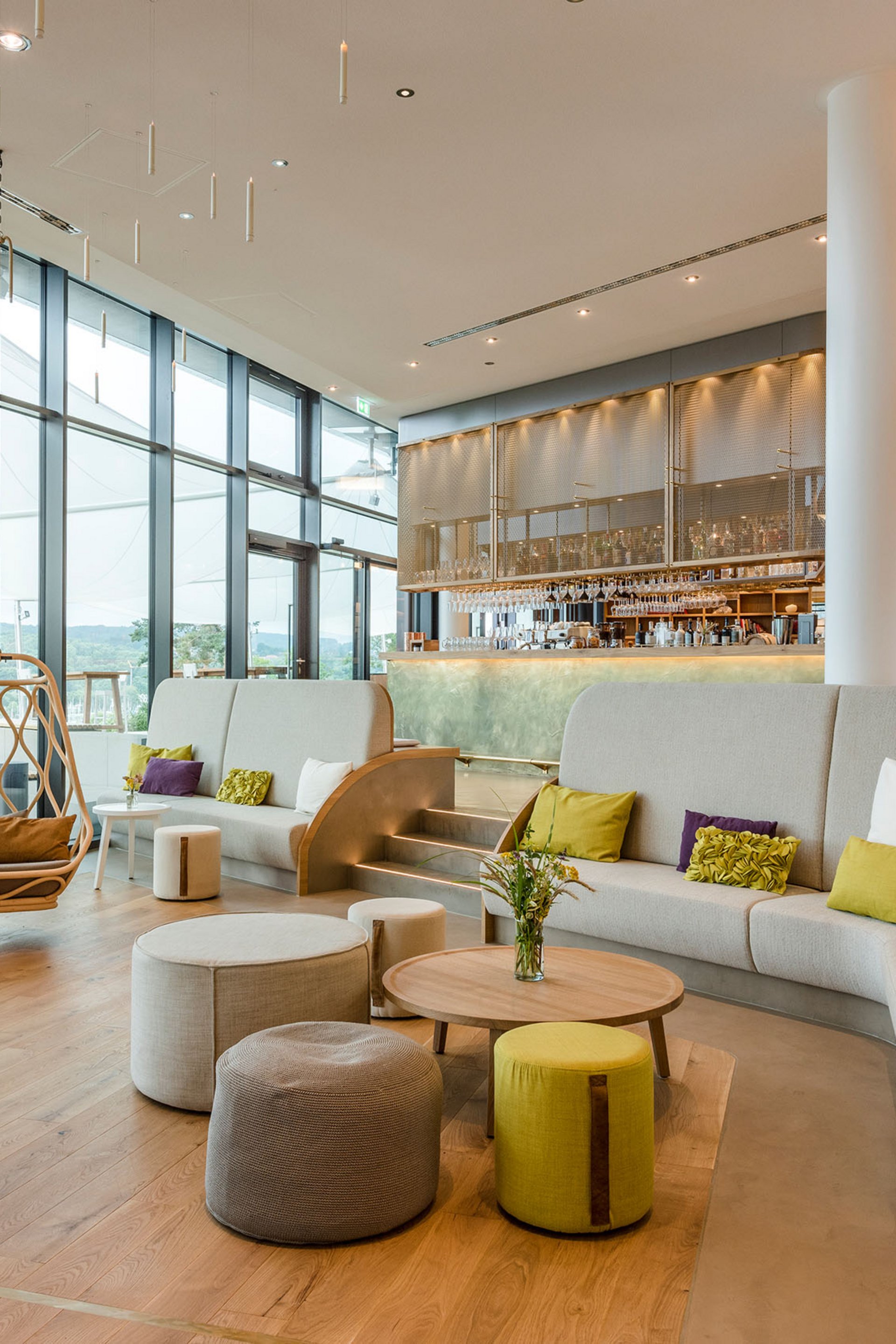 Salon moderne avec grandes fenêtres, sièges et un coin bar