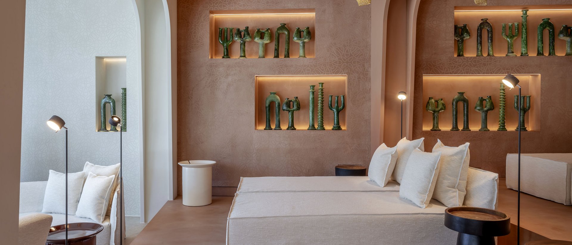 Salon moderne avec canapé beige, éclairage d'accent et sculptures vertes au mur.