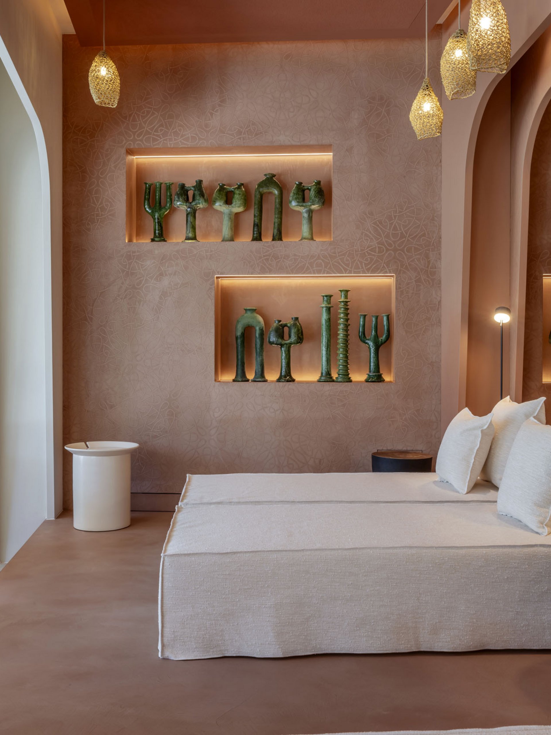 Modernes Wohnzimmer mit beiger Couch, Akzentbeleuchtung und grünen Skulpturen an der Wand.