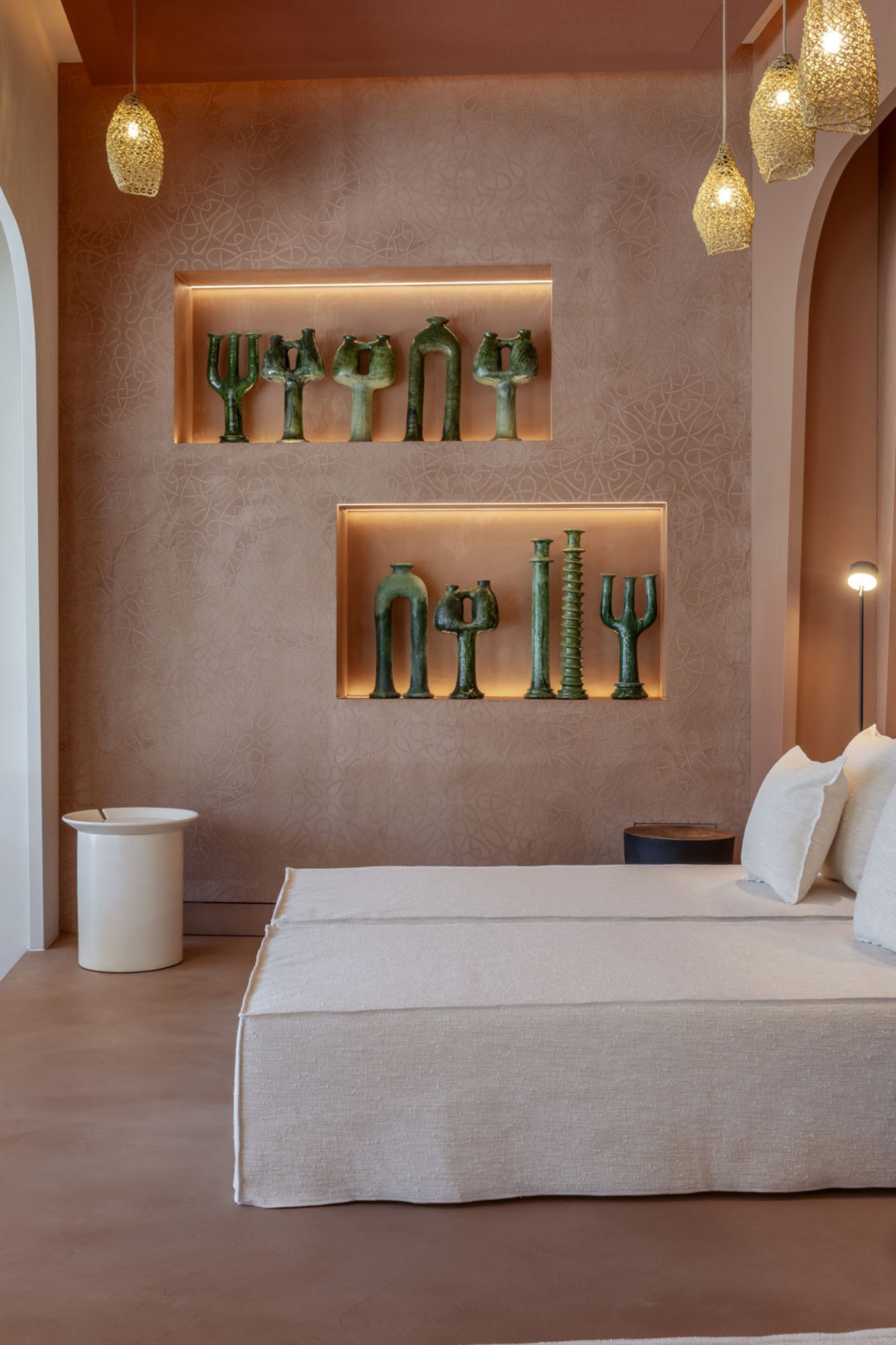 Salon moderne avec canapé beige, éclairage d'accent et sculptures vertes au mur.